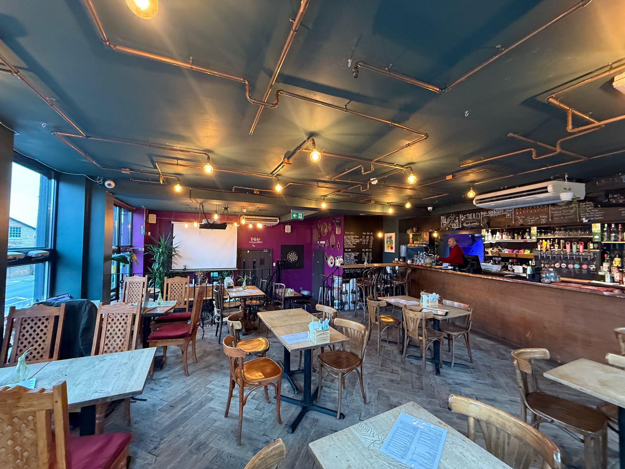 ChatGPT said:  Vibrant pub with exposed copper pipes, wooden tables, bar, projector screen, and dartboard, bookable via Conveenie.