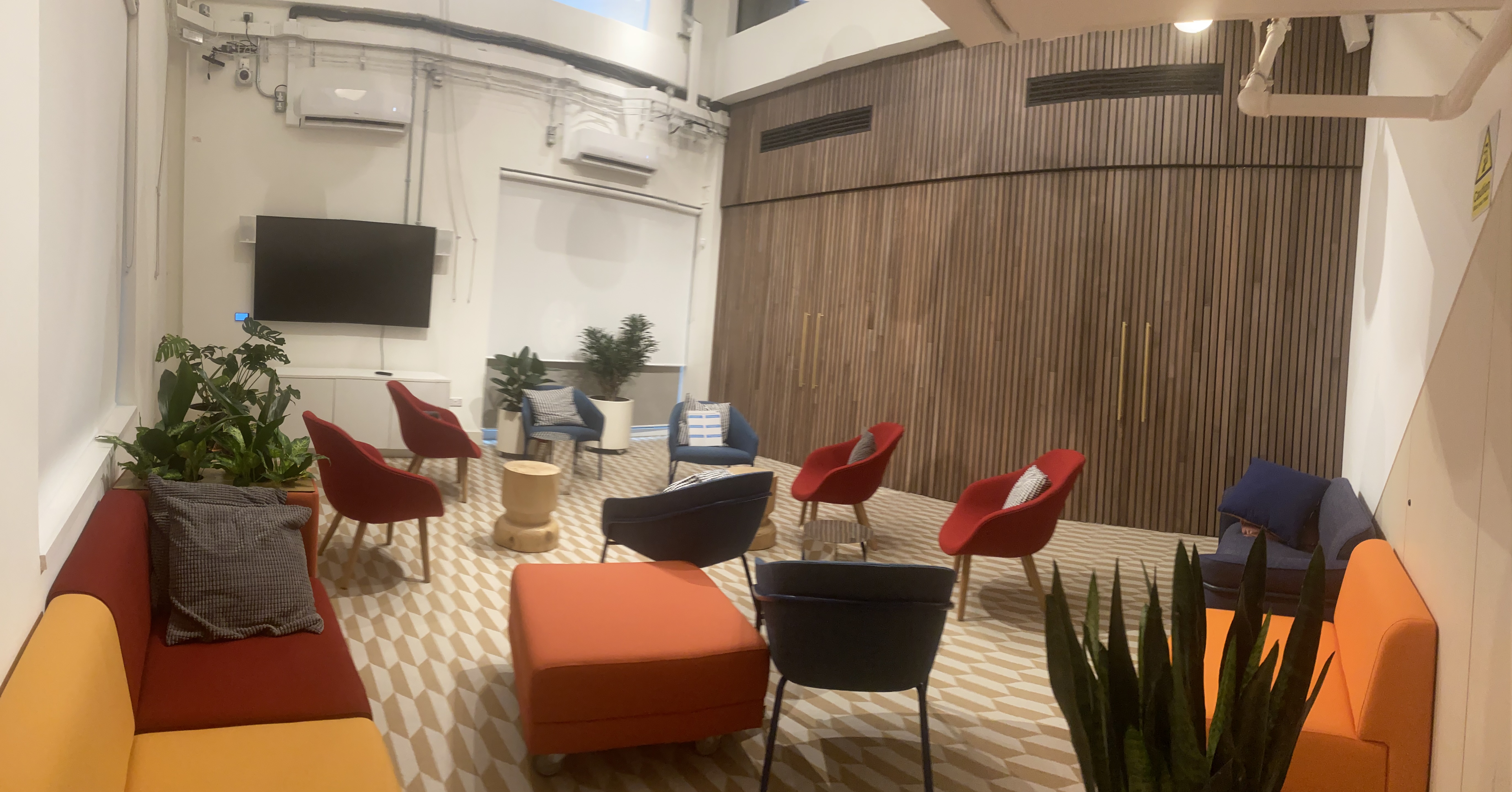 Lounge at Melanin Health & Wellness, 40-capacity, with wood-slatted wall, colorful sofas, modern chairs - book via Conveenie.