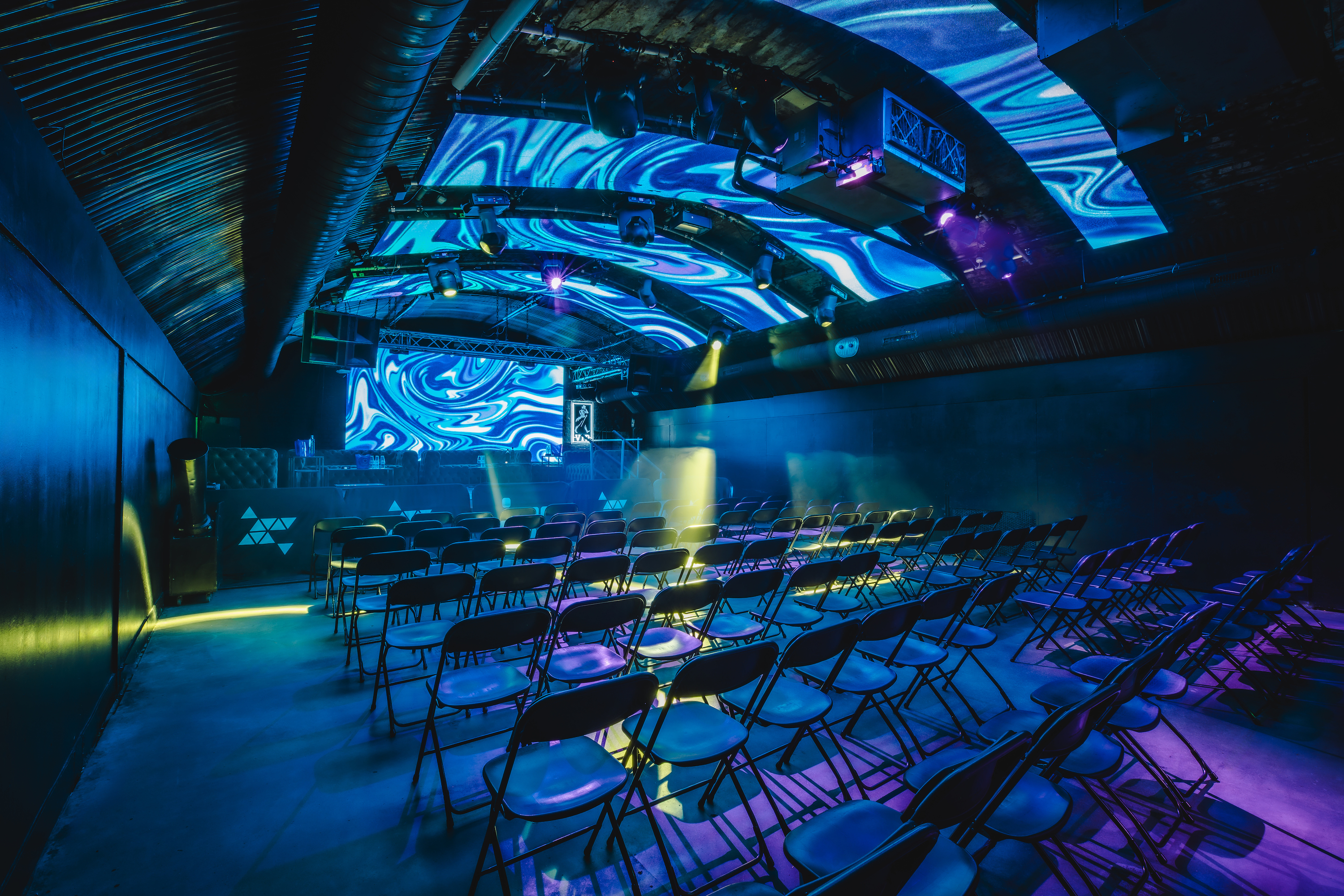 The Fire Main Room at Vauxhall Arches, a 600-capacity club space, is shown empty with dramatic red and blue spotlights illuminating the floor.