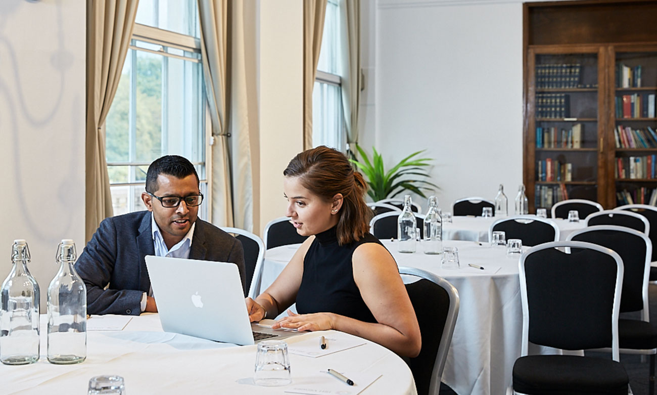Two delegates collaborating on a laptop in the traditionally decorated Gulbenkian room, showcasing a professional workshop environment.