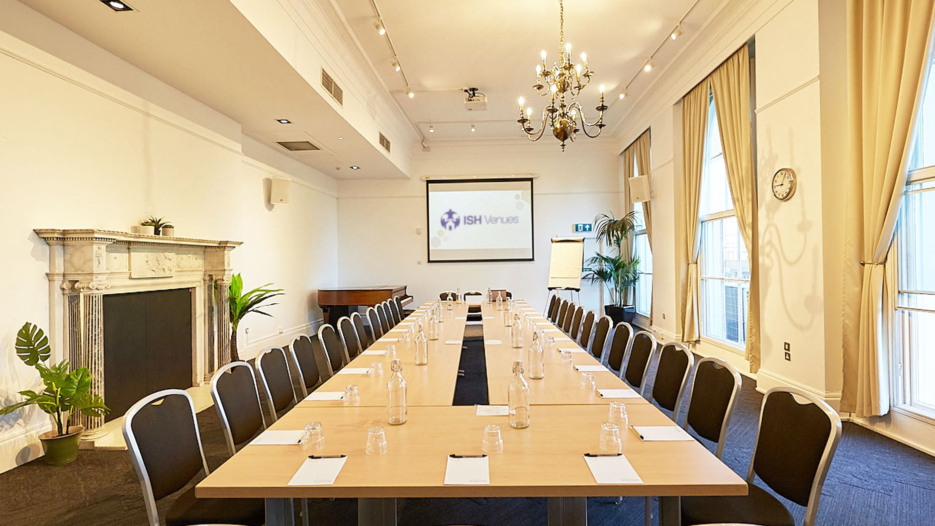 Large boardroom table setup in The Gulbenkian, highlighting modern AV equipment, a chandelier, and bright, airy atmosphere.
