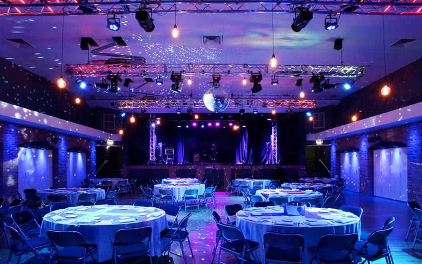 Venue 1 gala setup with vibrant blue and purple mood lighting, a disco ball, and multiple banquet tables.
