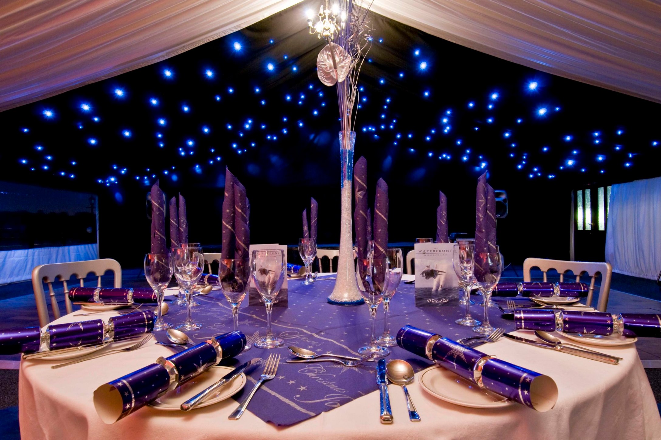 Festive Christmas table setting at ISH Venues with purple crackers and a starry-night ceiling light effect.