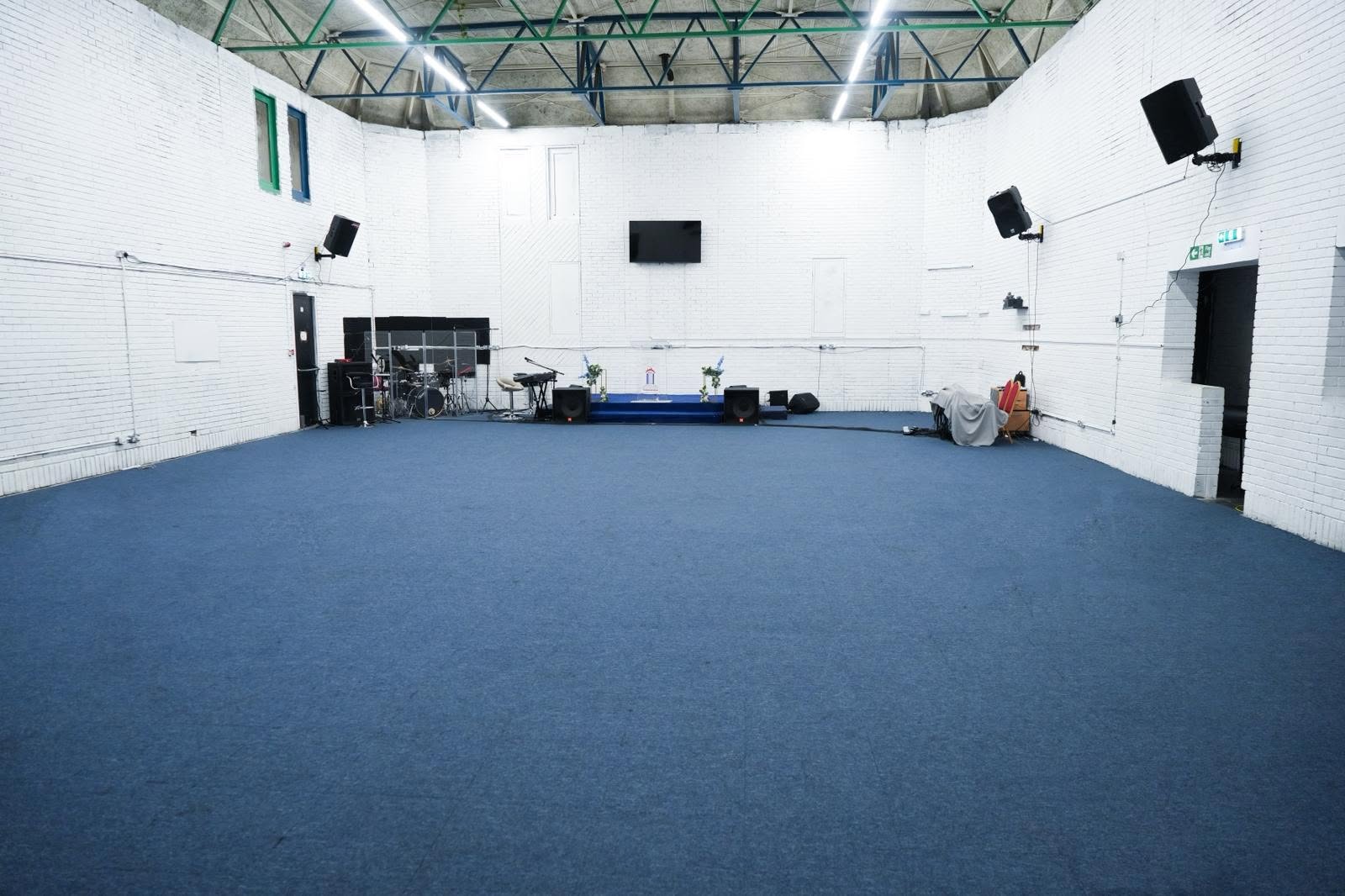 Vast Canning Town event hall with an open-plan layout, high industrial ceilings, and a built-in performance stage.