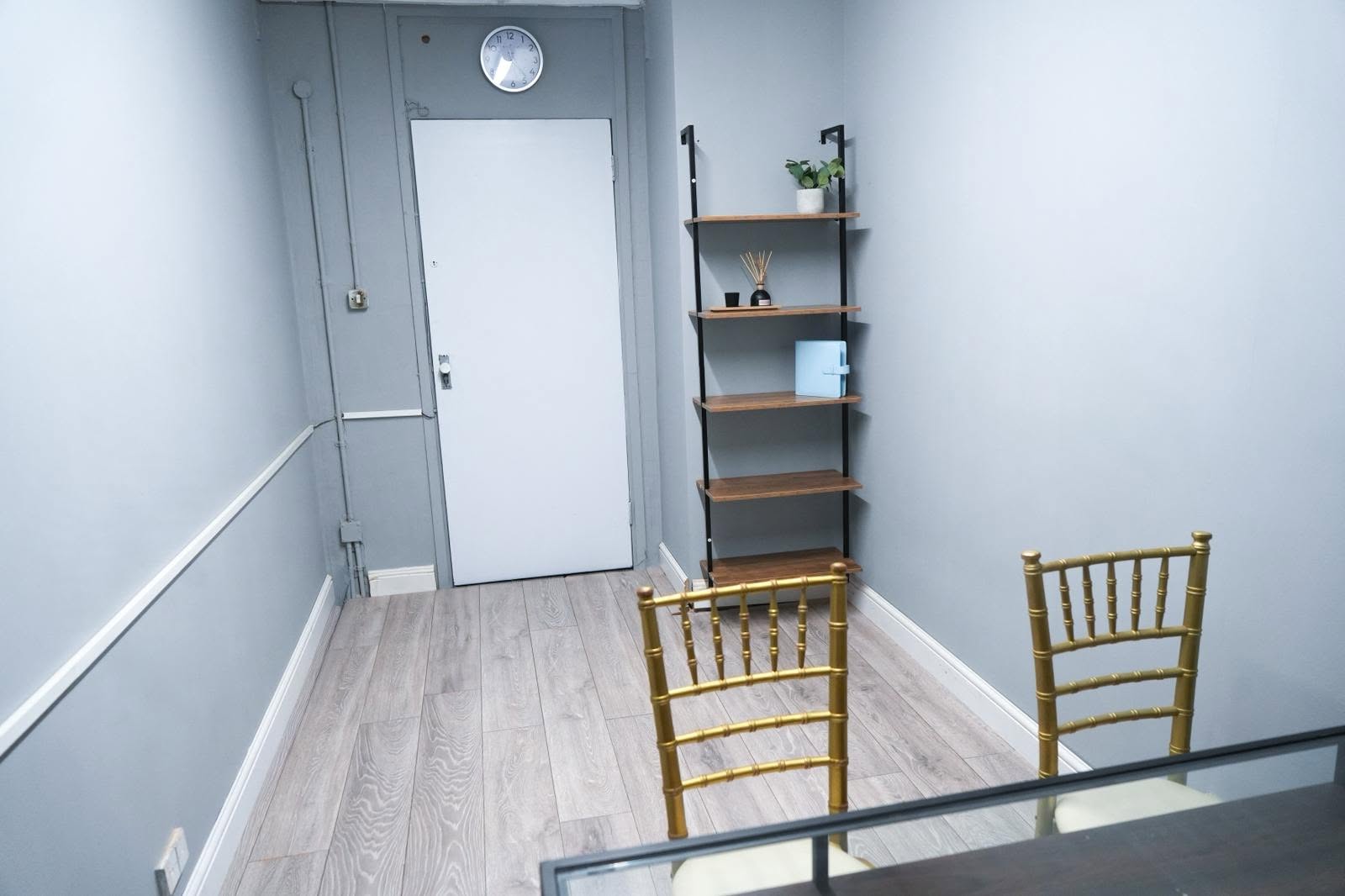 Intimate East London workspace showcasing decorative shelving, light wood flooring, and a calm, professional design.