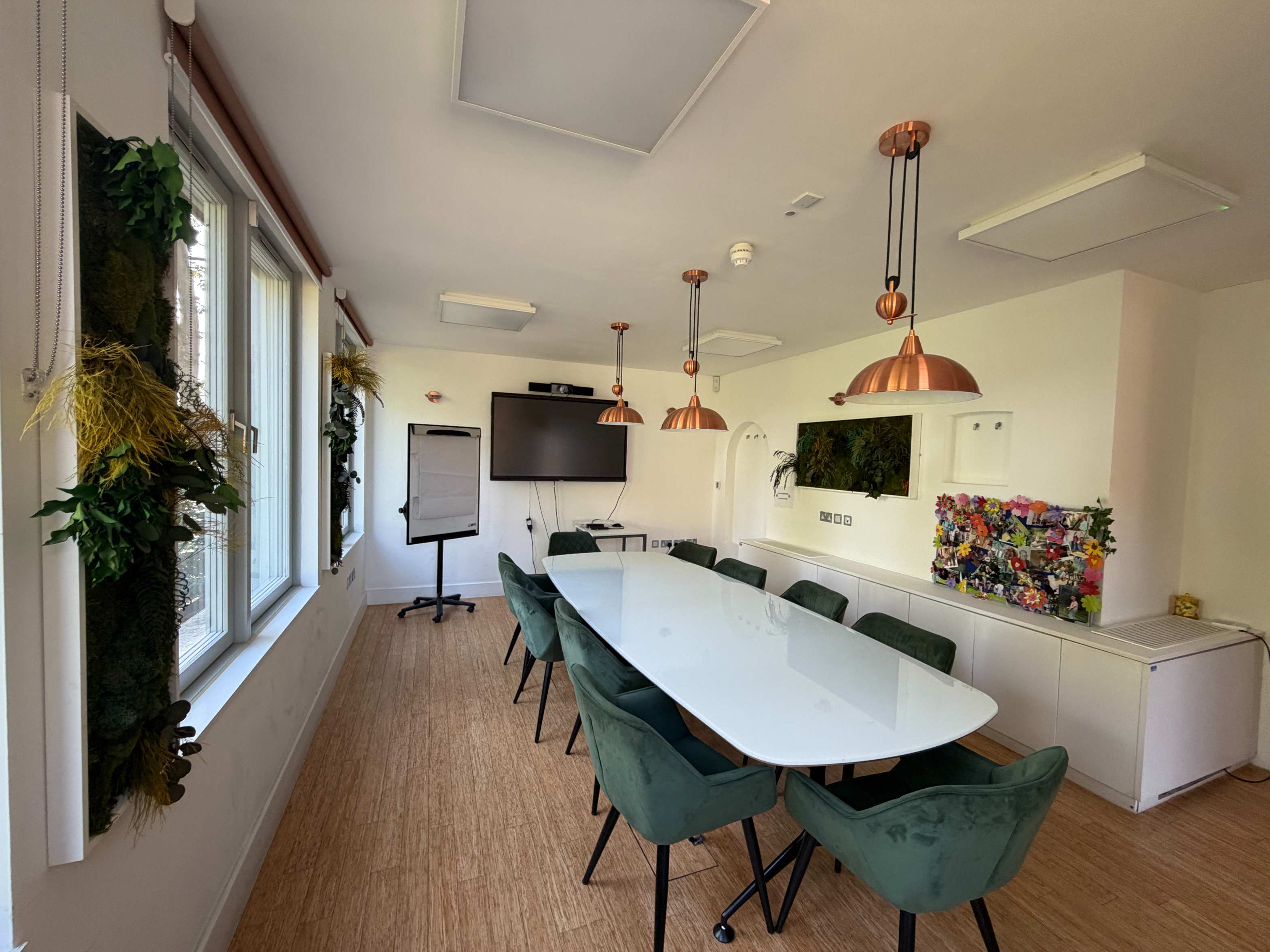 Centre 404 Boardroom with glass table, green chairs and copper pendant lighting