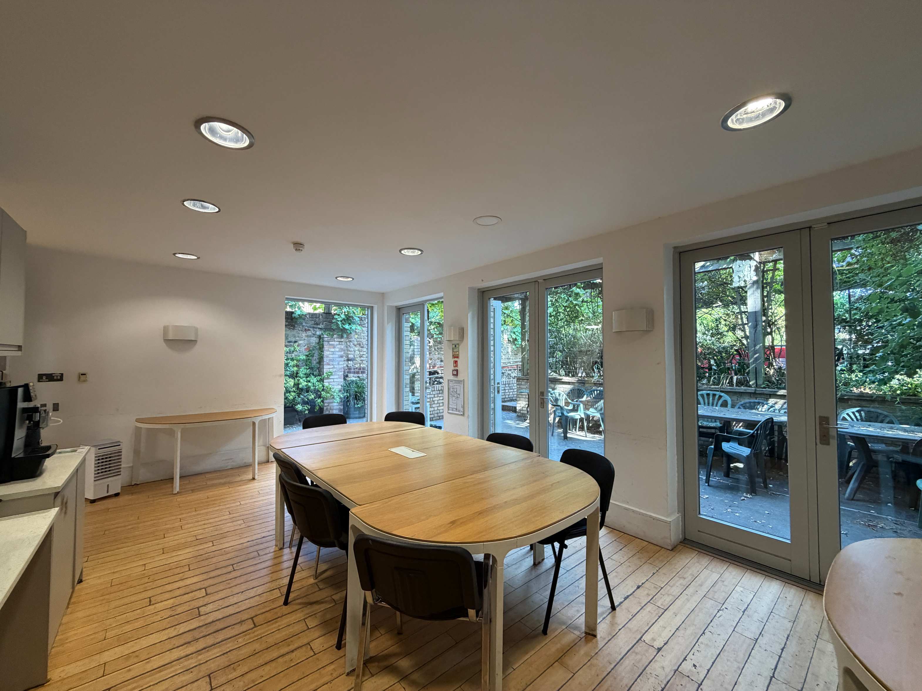 Garden Room at Centre 404 with oval wooden table, wooden flooring and glass doors overlooking the patio