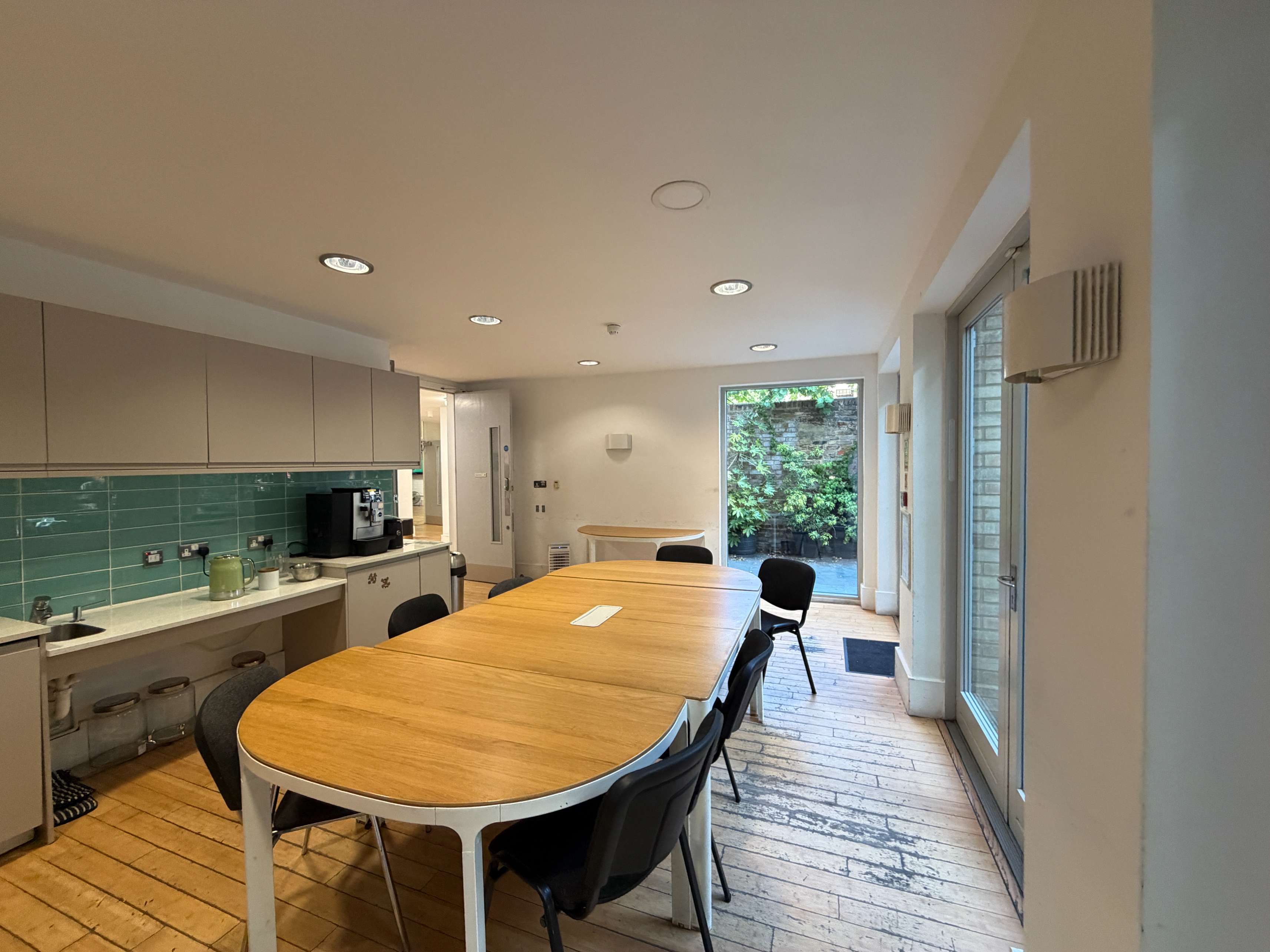 Garden Room at Centre 404 with seating table and adjoining kitchenette, garden views through glass doors