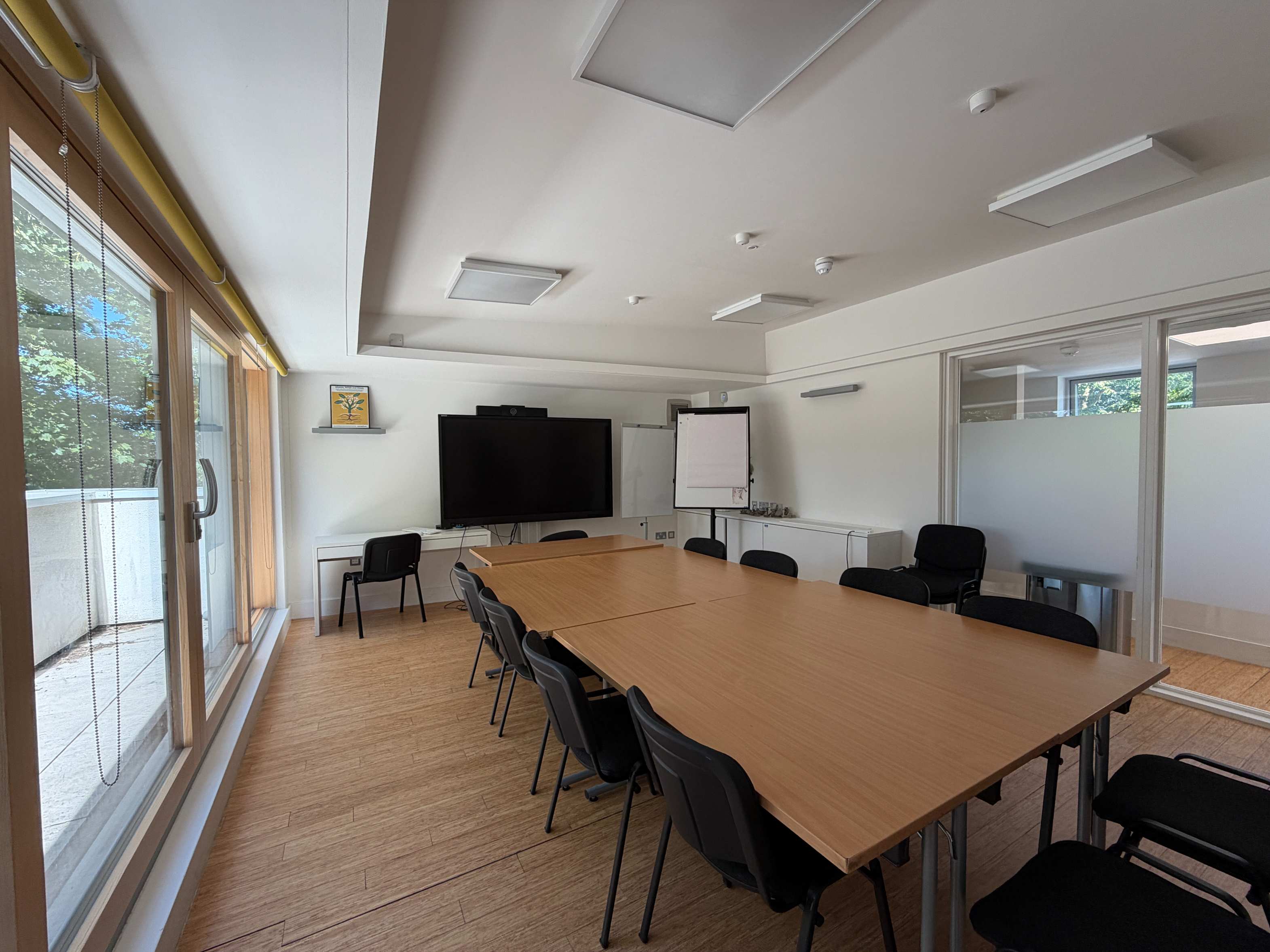 Training Room at Centre 404 with wall-mounted display screen and flipchart, seating around a long table