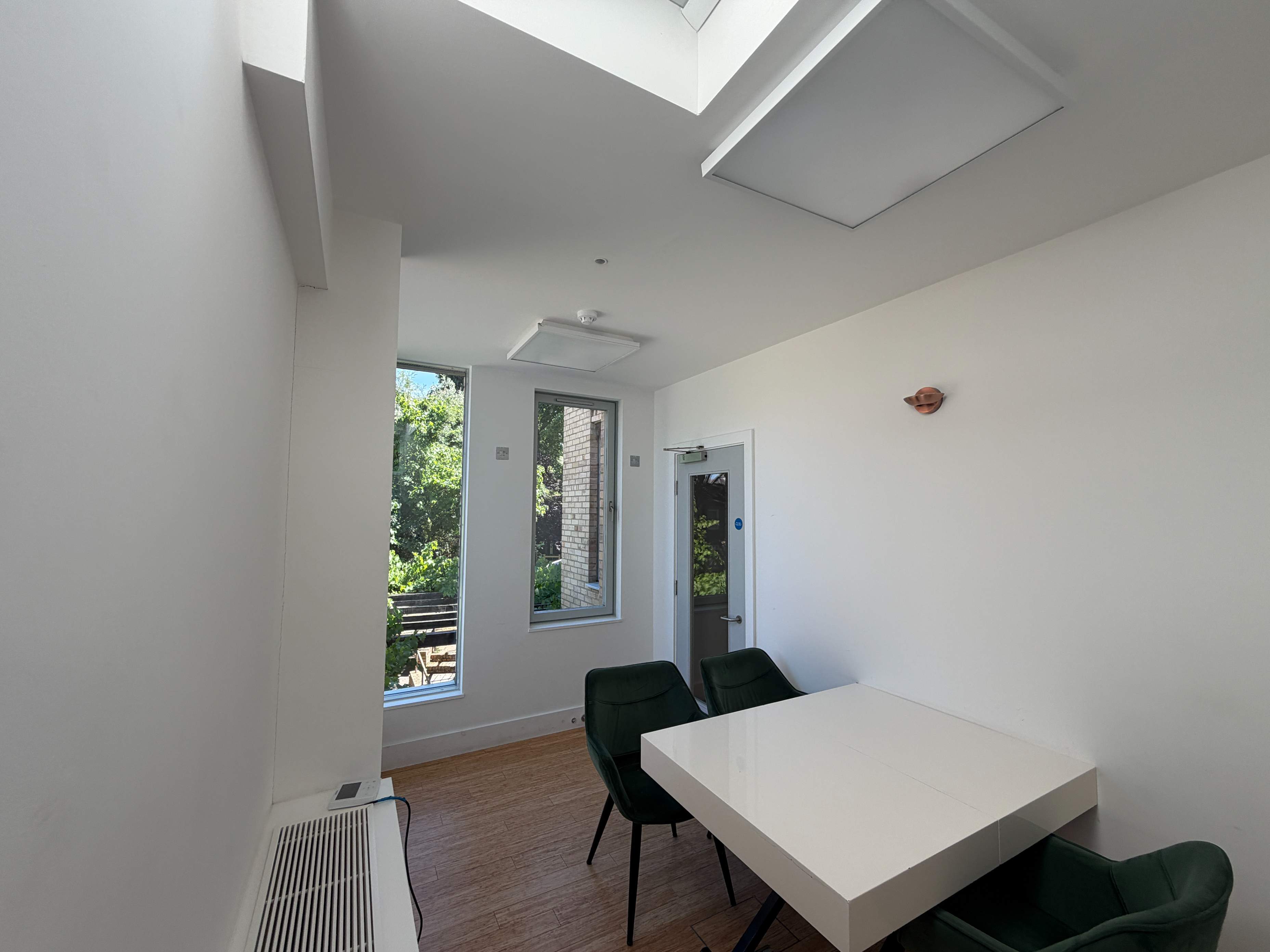 Workspace at Centre 404 with white table, chairs and doors opening onto a balcony