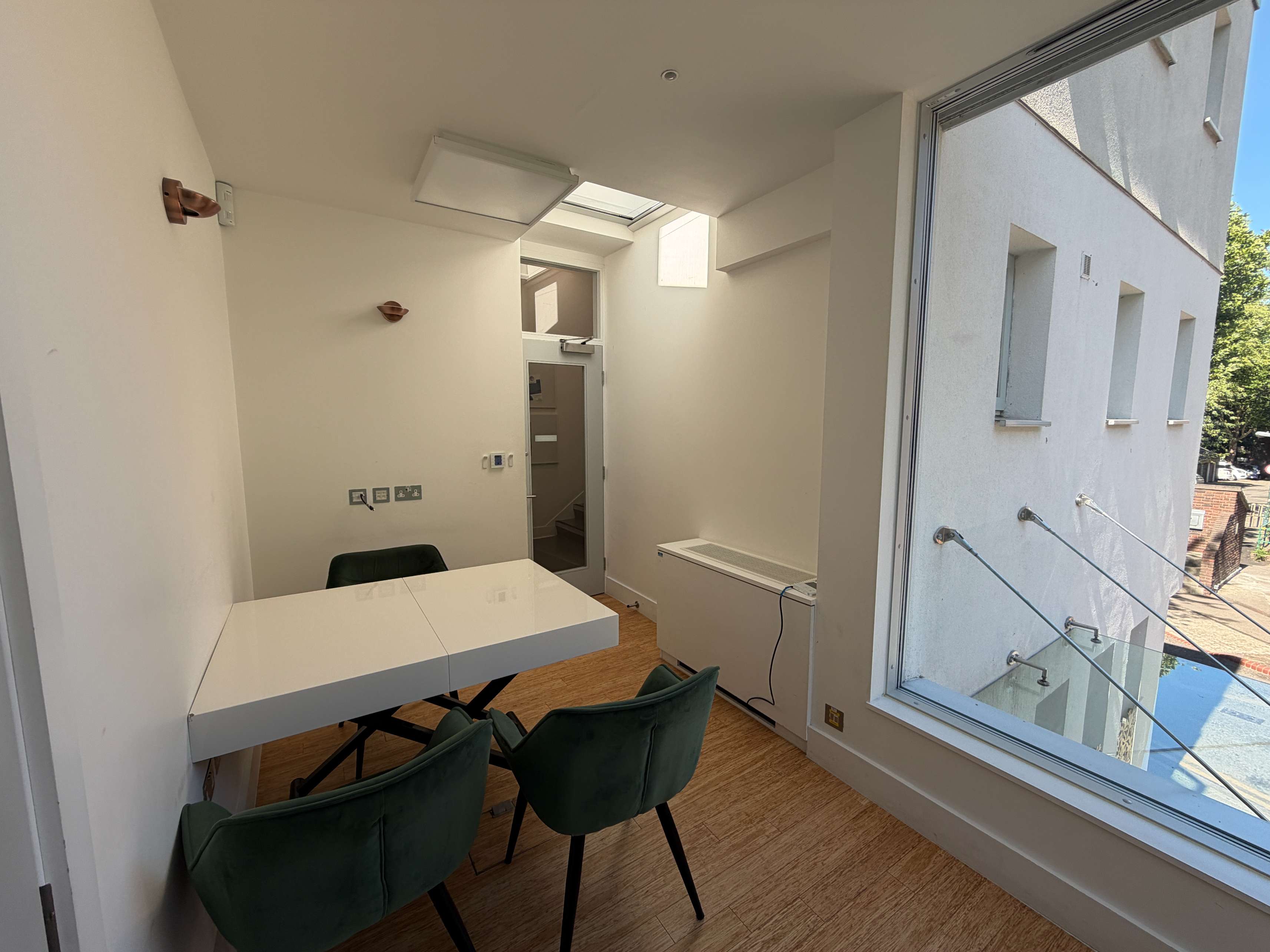 Workspace at Centre 404 with white desk, green upholstered chairs and window seating