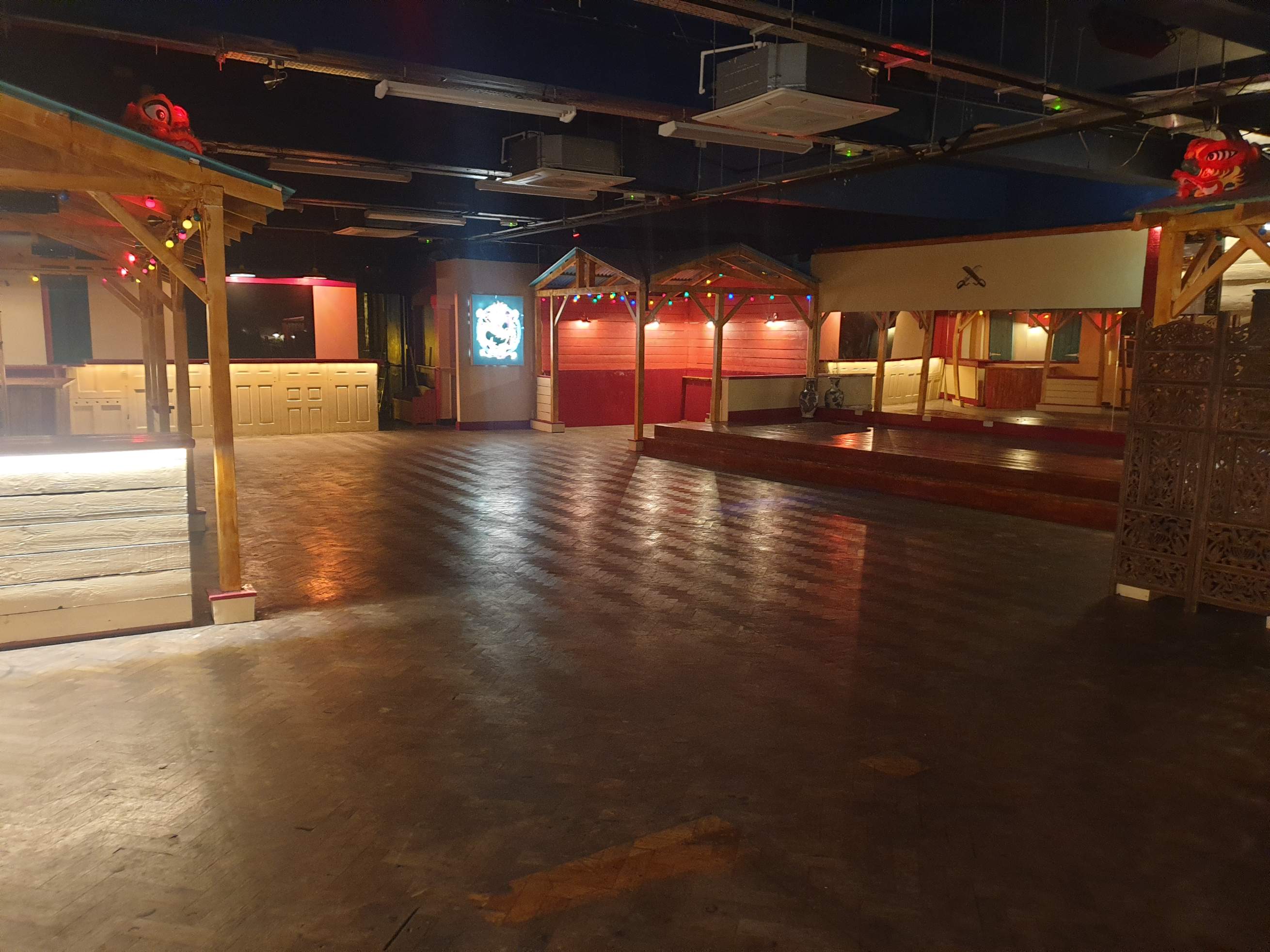 Wide view of the main hall at Zhulin Hidden Village in London, showcasing the versatile open floor space with atmospheric lighting for events, perform
