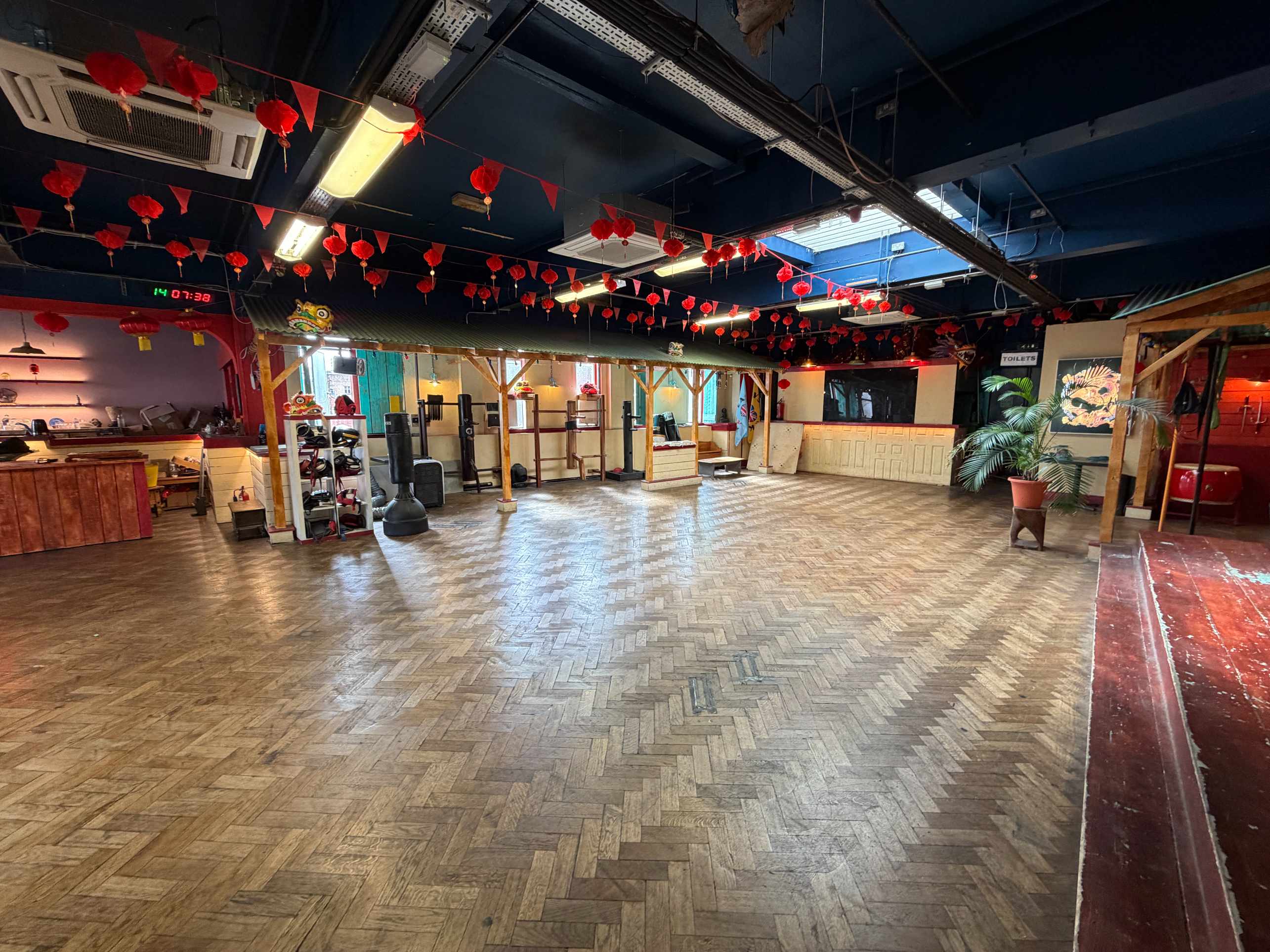 Zhulin Hidden Village community hall with wooden floor, red lanterns, and a bright open area for classes or events