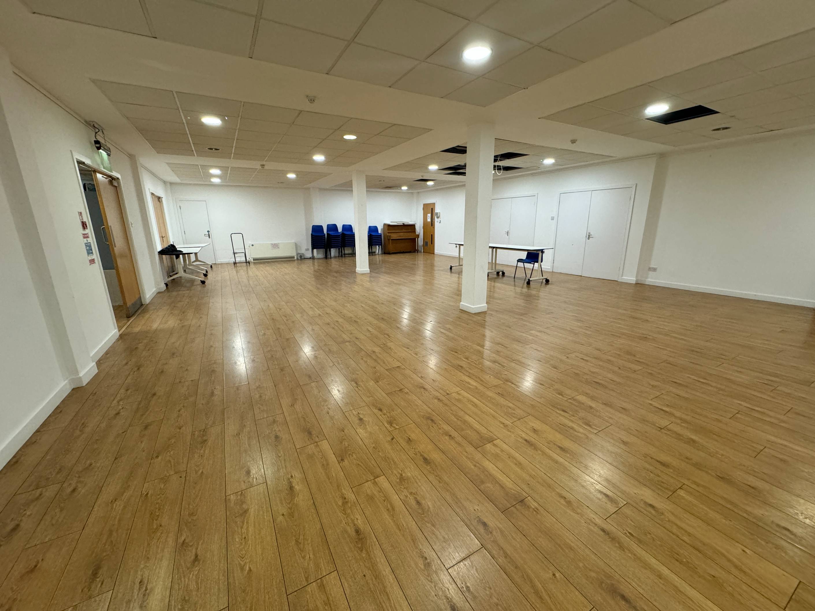 Interior hall view of the refurbished Crypt showing spacious layout with stacked chairs and tables for 75 attendees