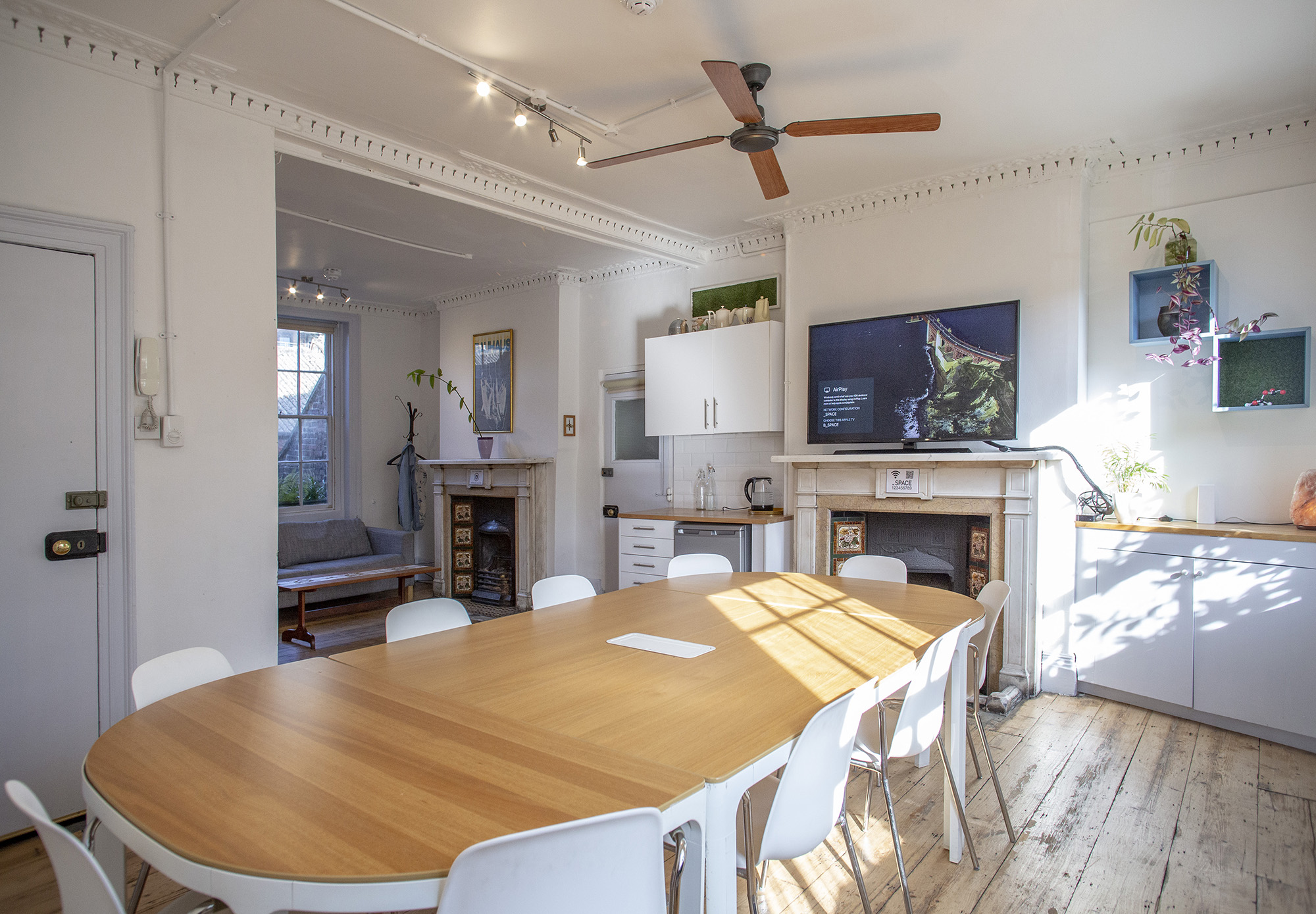 Airy meeting room hire in London at The Office, Anomalous Space, with a large table, TV, and kitchenette, perfect for 15 guests.