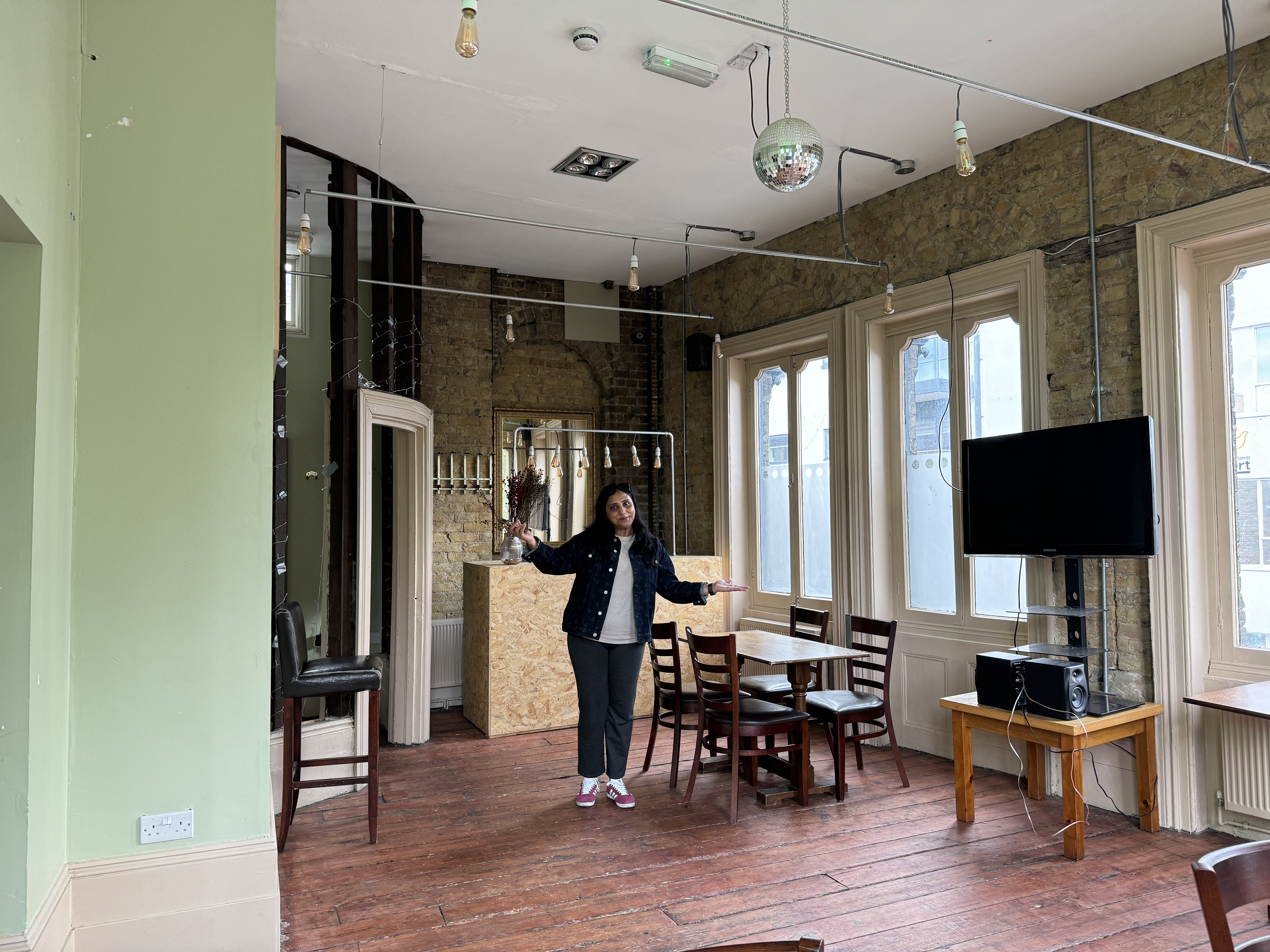 The Phoenix pub’s function room with wooden flooring, high ceilings, hanging lights, disco ball, and large sash windows, showing the spacious event ar