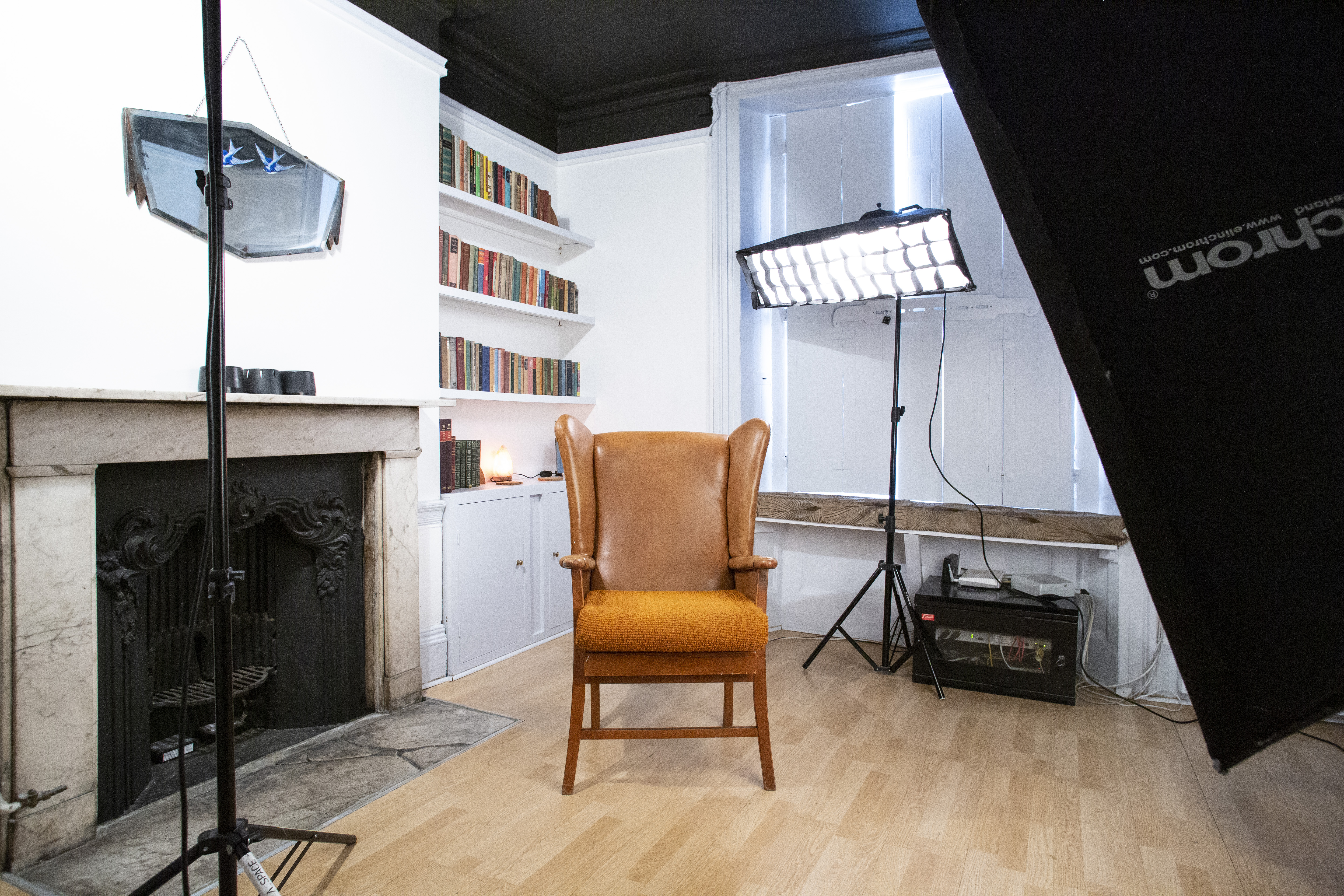 A London photography studio, at Islington for 10, featuring a fireplace, vintage armchair, and professional lighting equipment.