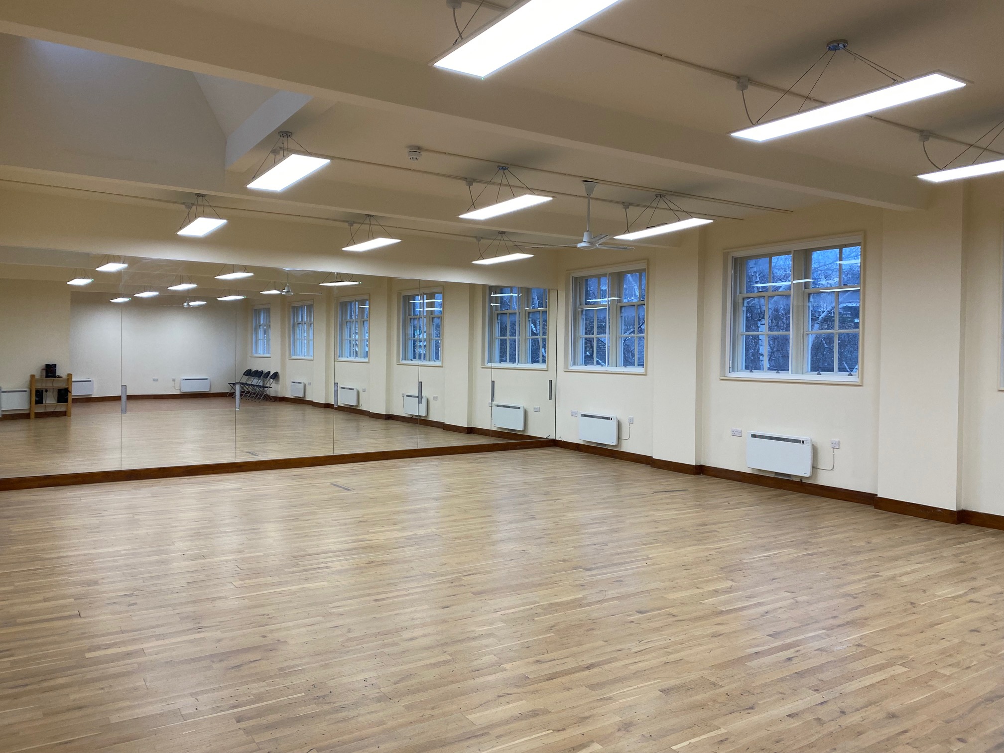 Bright and airy dance studio with full-length mirrored wall and sprung flooring, ideal for movement classes
