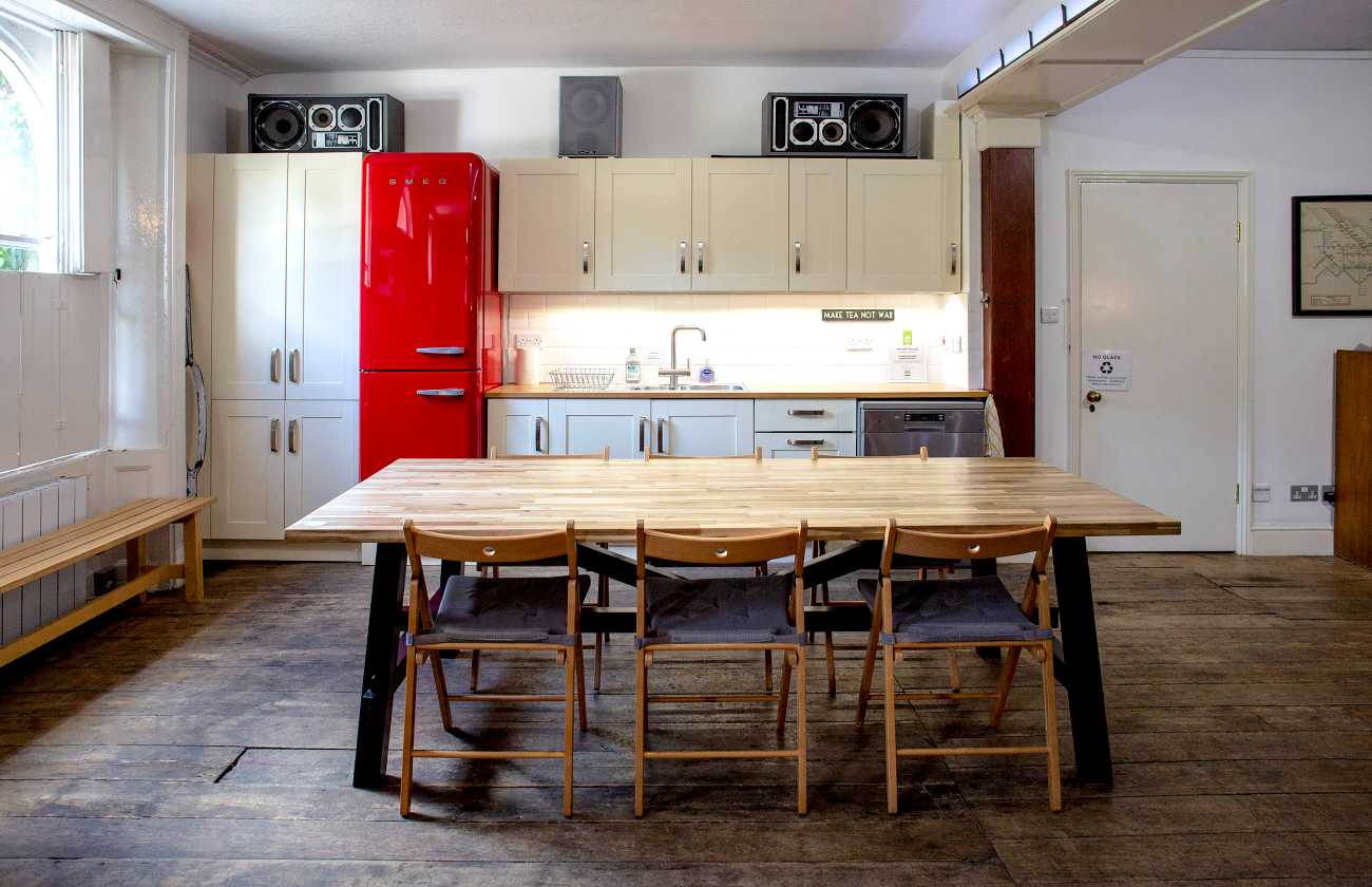 Communal party room London at The Home, Anomalous Space, featuring a kitchen, large table, and bright red SMEG fridge, a perfect venue hire near me.