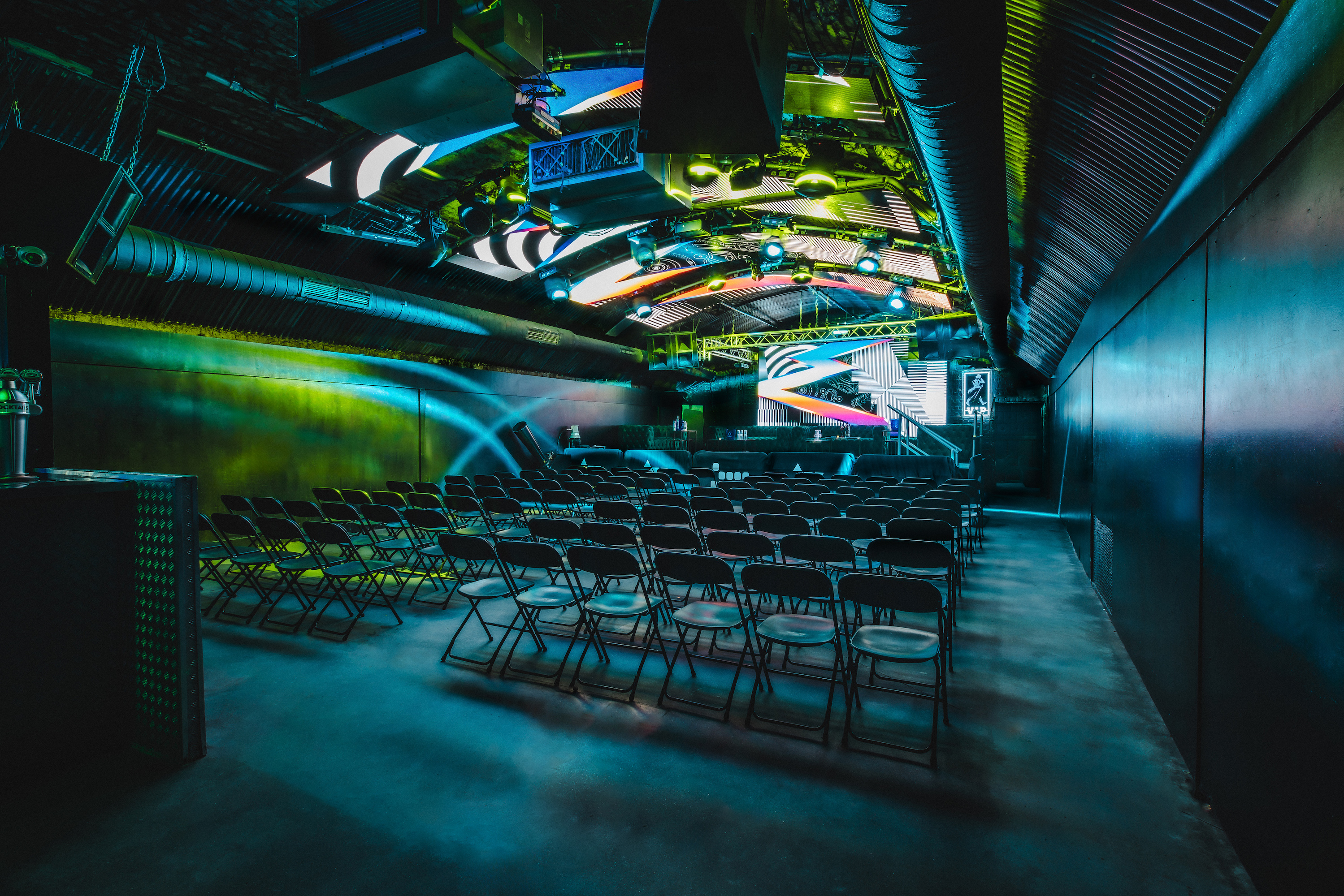 The Fire Main Room at Vauxhall Arches, bookable through Conveenie, is set for a 600-person conference with a lectern, screen, and light grid.
