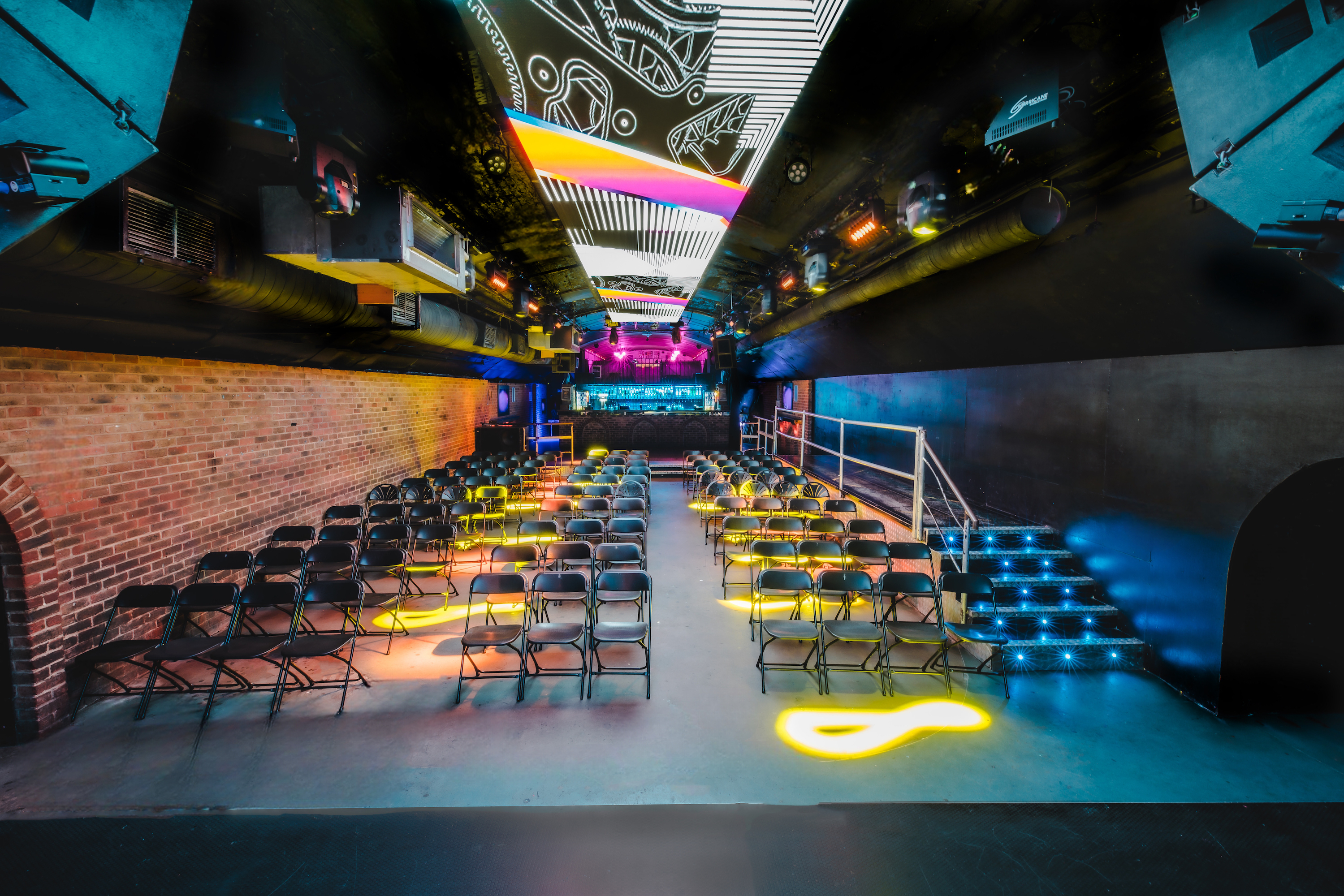 The spacious Fire Main Room at Vauxhall Arches for 600, shown as an empty club space with dynamic red and blue ceiling spotlights.