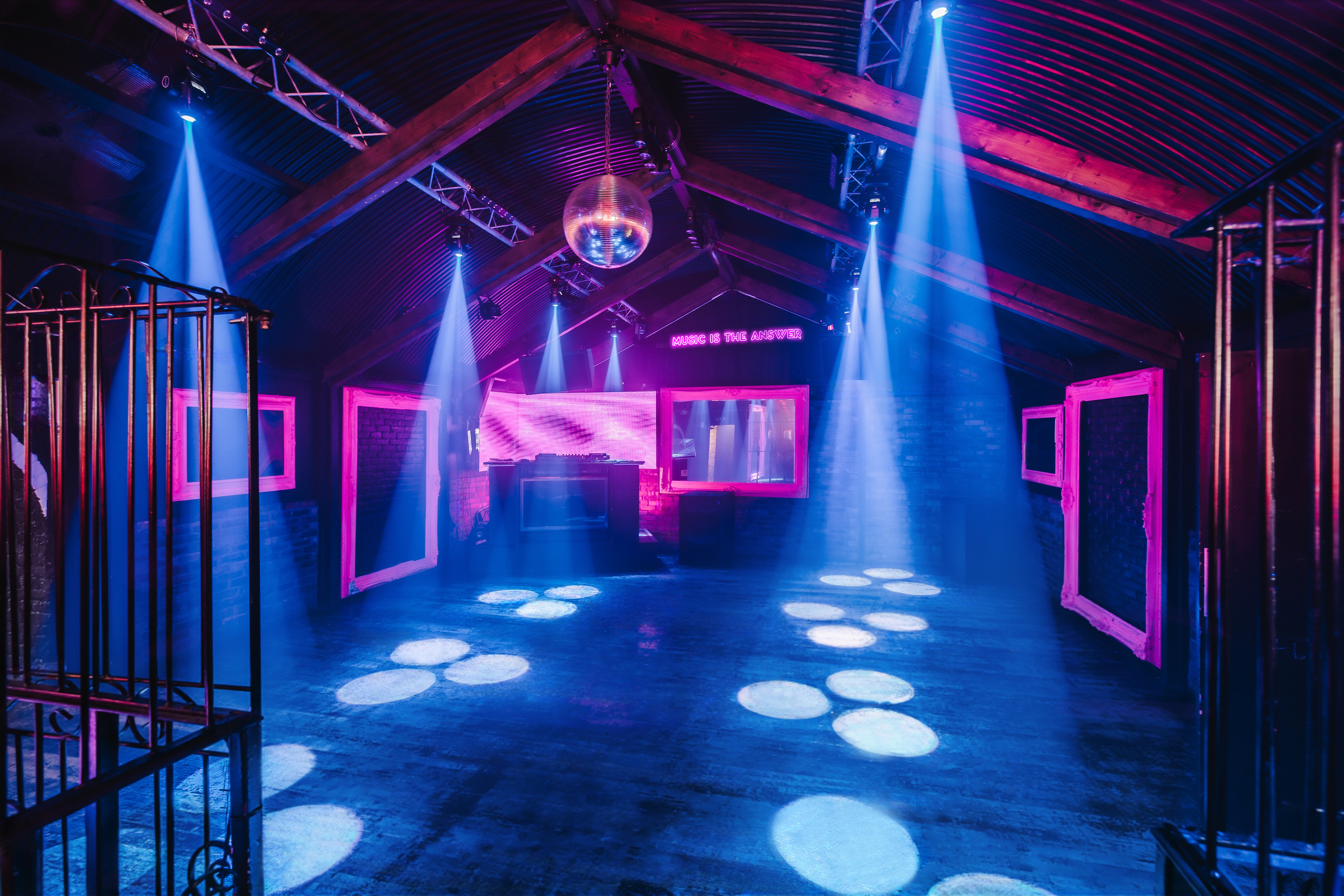 The main club room at Protocol, Vauxhall Arches, for 350, features a DJ booth, exposed beams, and dynamic blue spotlights for a party atmosphere.