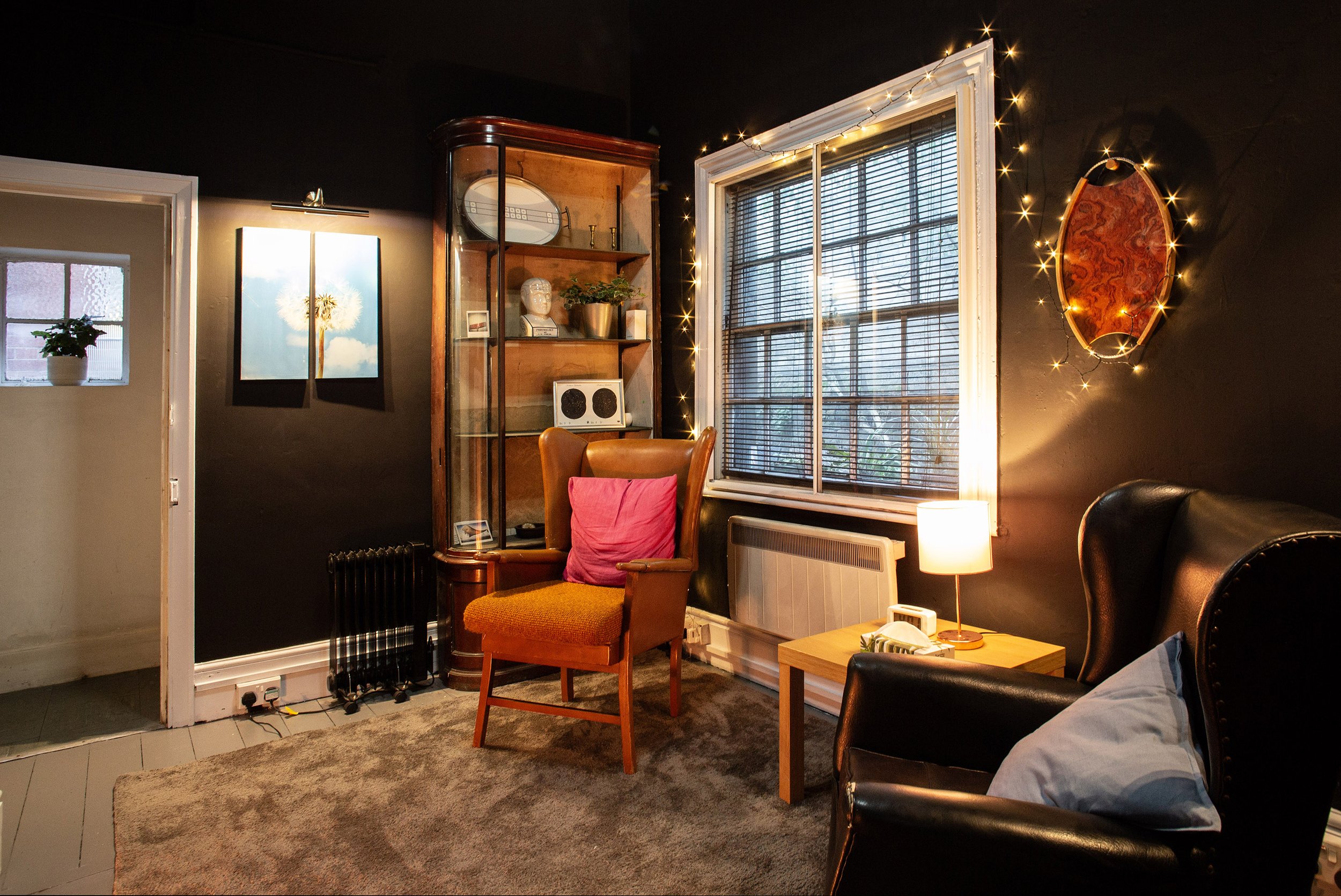 Cosy sitting area in The Den, Anomalous Space, a small meeting room for 3, featuring vintage leather armchairs and warm fairy lights.