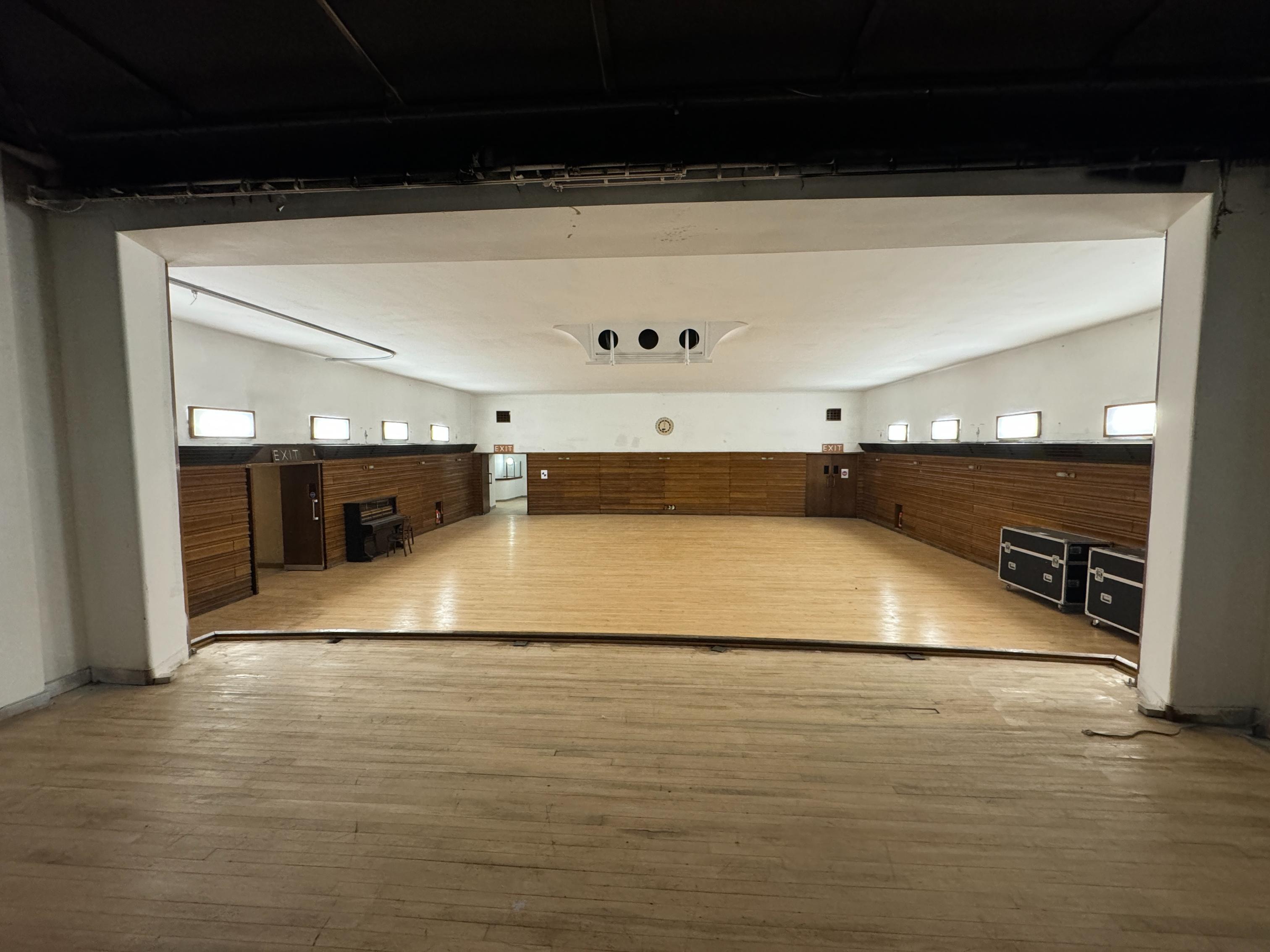 A wide-angle view of the Minor Hall, showing the spacious wooden floor and the stage at the far end. Book via Conveenie.