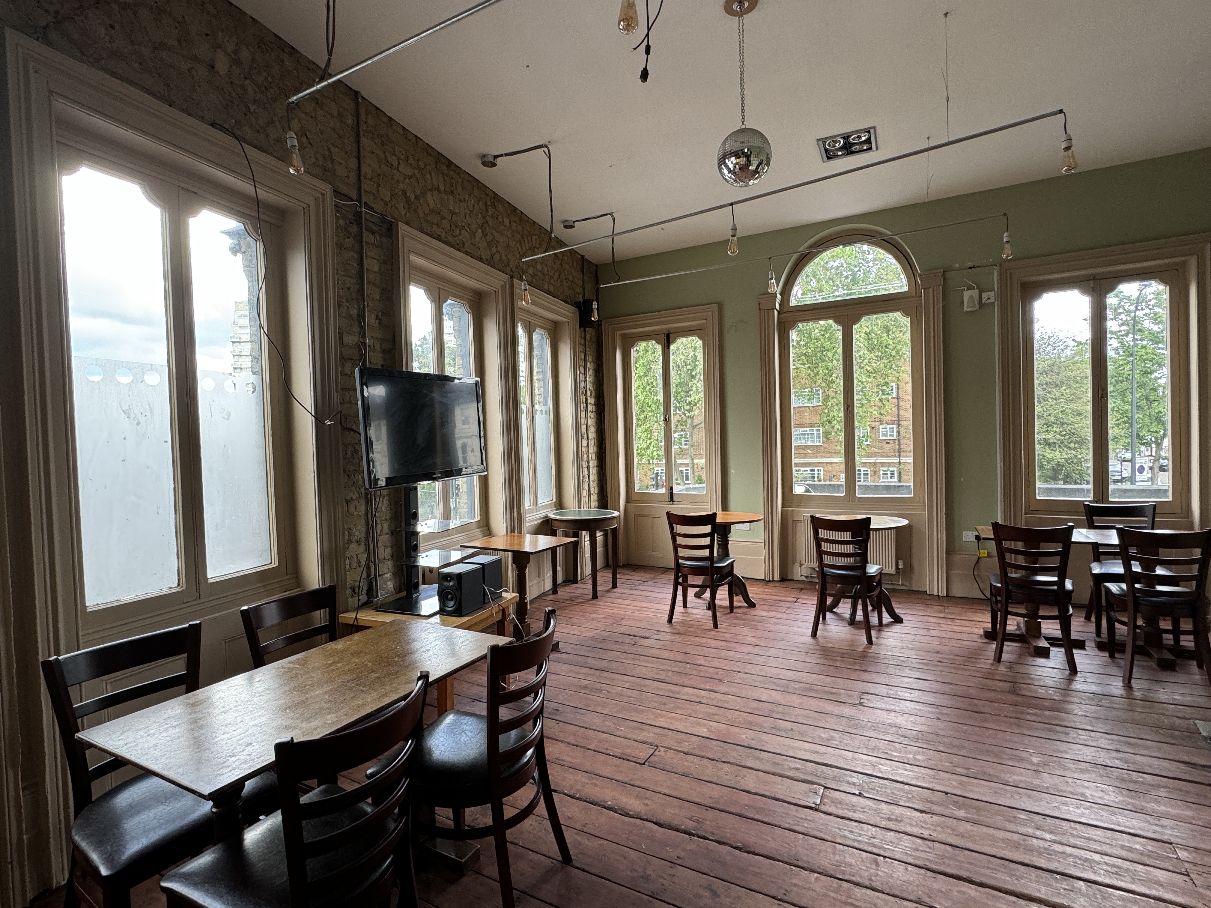 Interior of the function room at The Phoenix: wooden floor, seating, tall windows letting in natural light, and warm décor