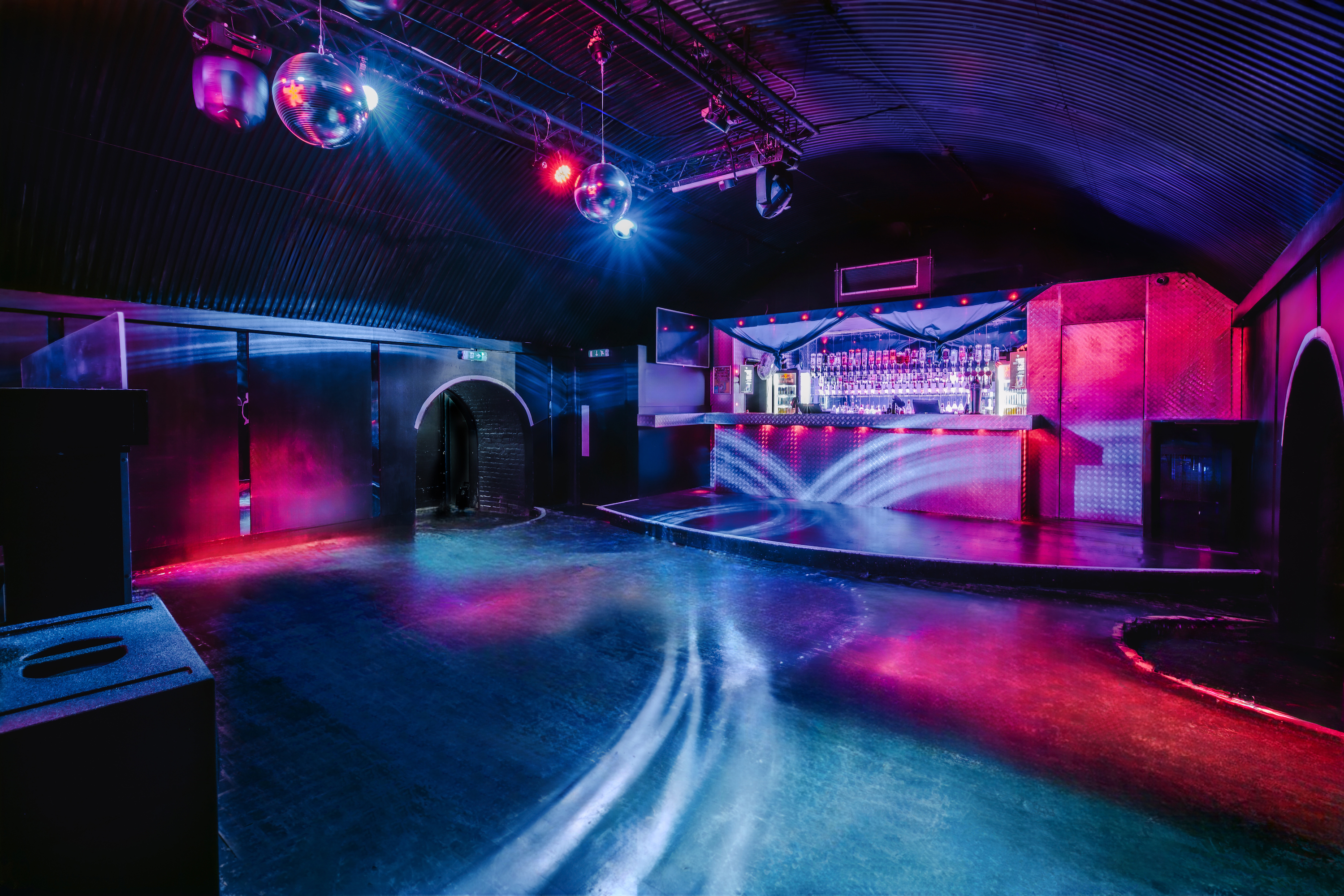 The futuristic bar at Protocol, Vauxhall Arches, a 350-capacity venue, features a corrugated arch ceiling, disco balls, and pink and blue lighting.