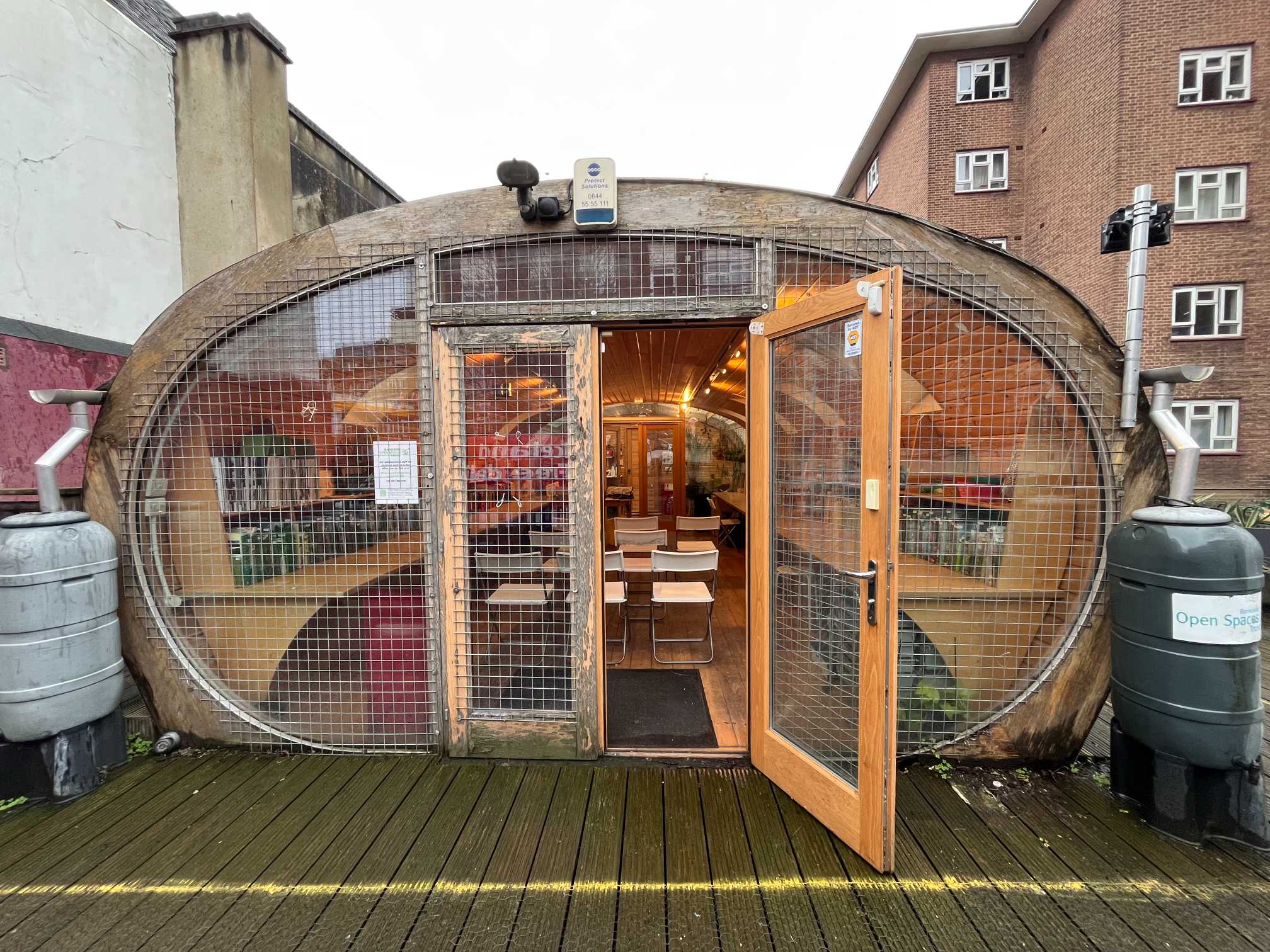 A quirky, boat-shaped building with a large, arched glass front, and an open door showing the interior.
