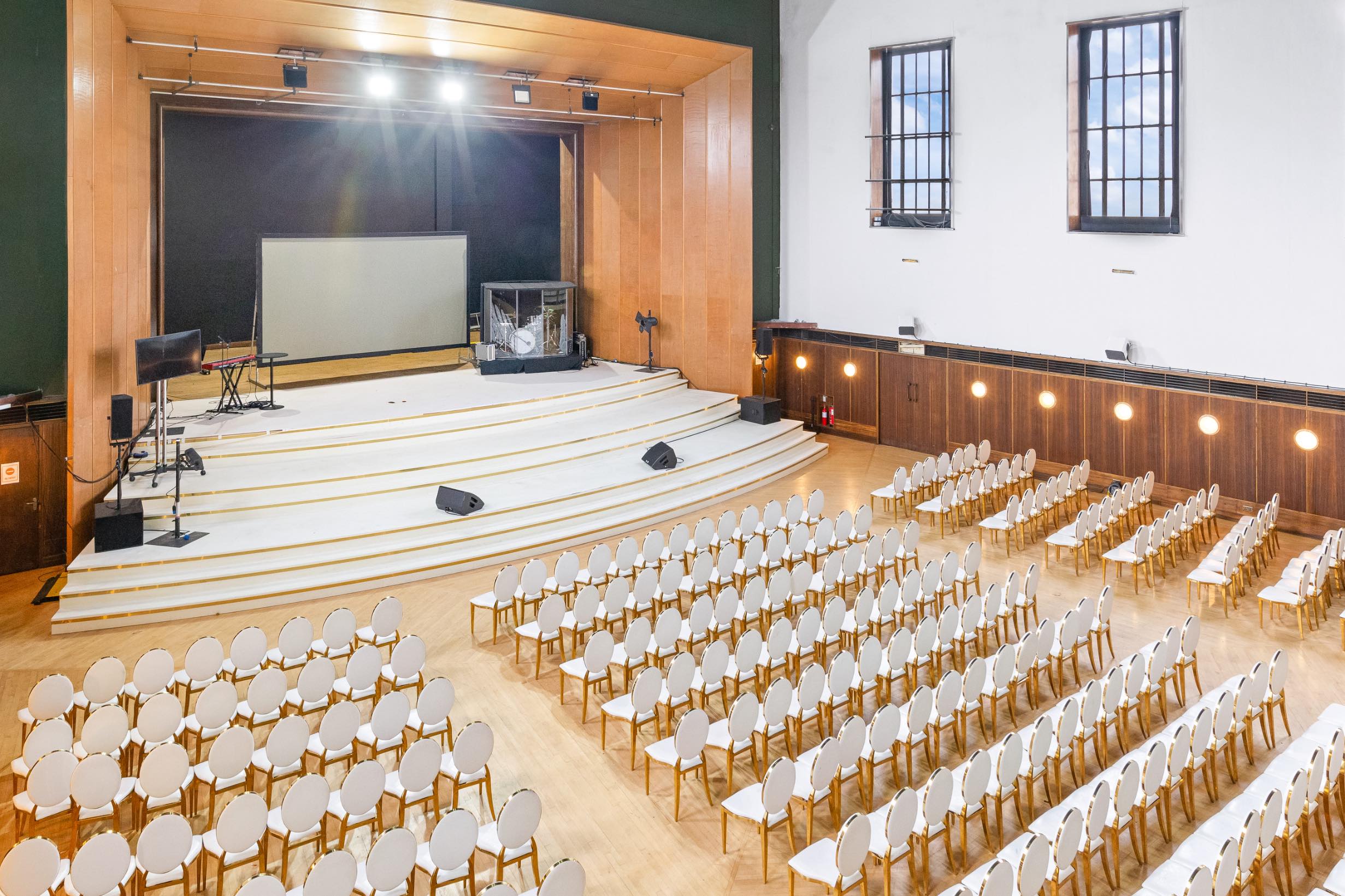 Spacious auditorium with stage and rows of chairs set up for a conference or live event in the heart of Greenwich