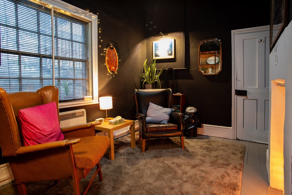 ChatGPT said:  Cozy sitting area in The Den, Anomalous Space, a small London meeting room for 3 with vintage leather chairs and warm lighting.