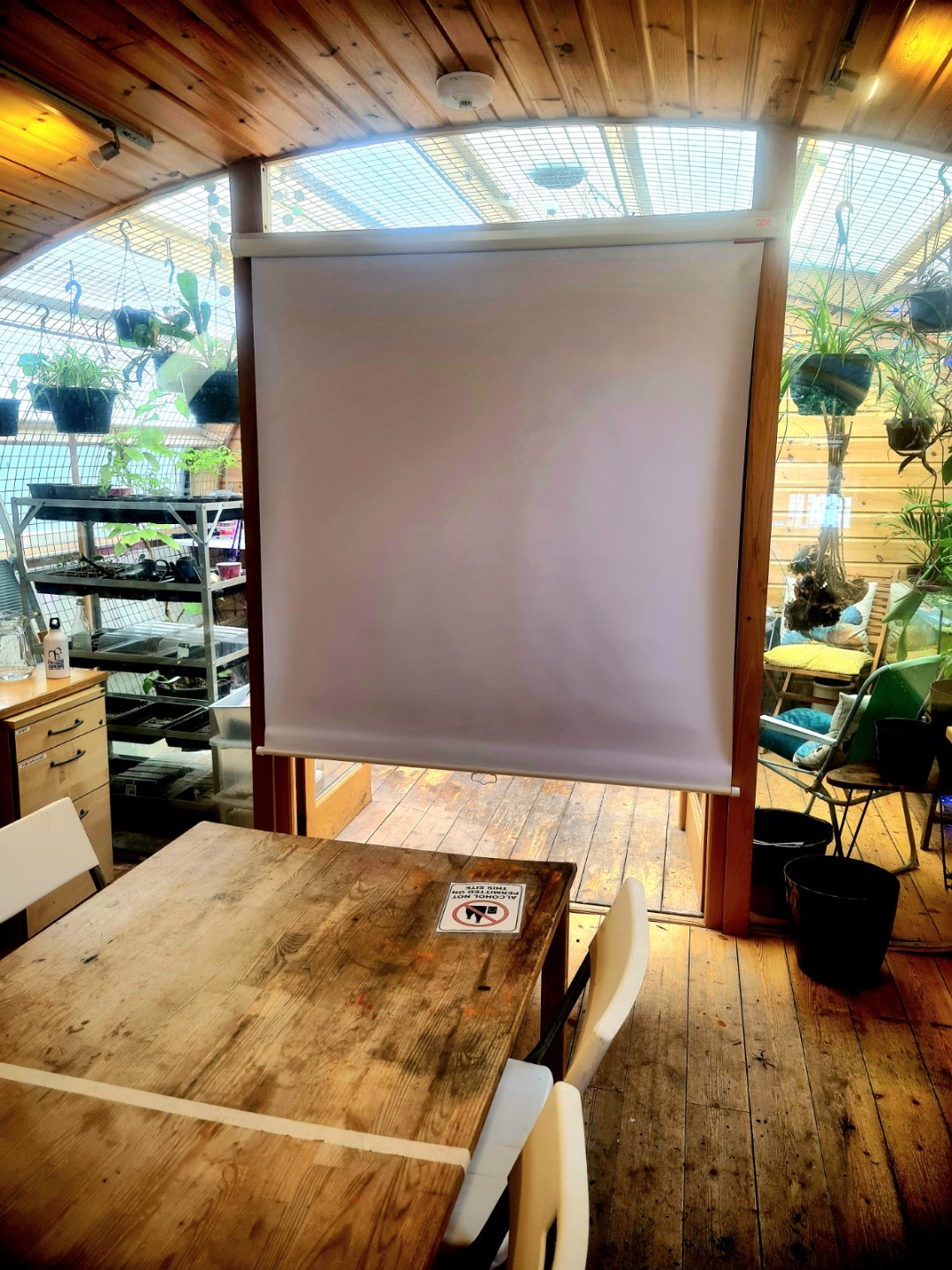 A small wooden-paneled room with a vaulted ceiling and a blank projector screen hanging in a doorway.