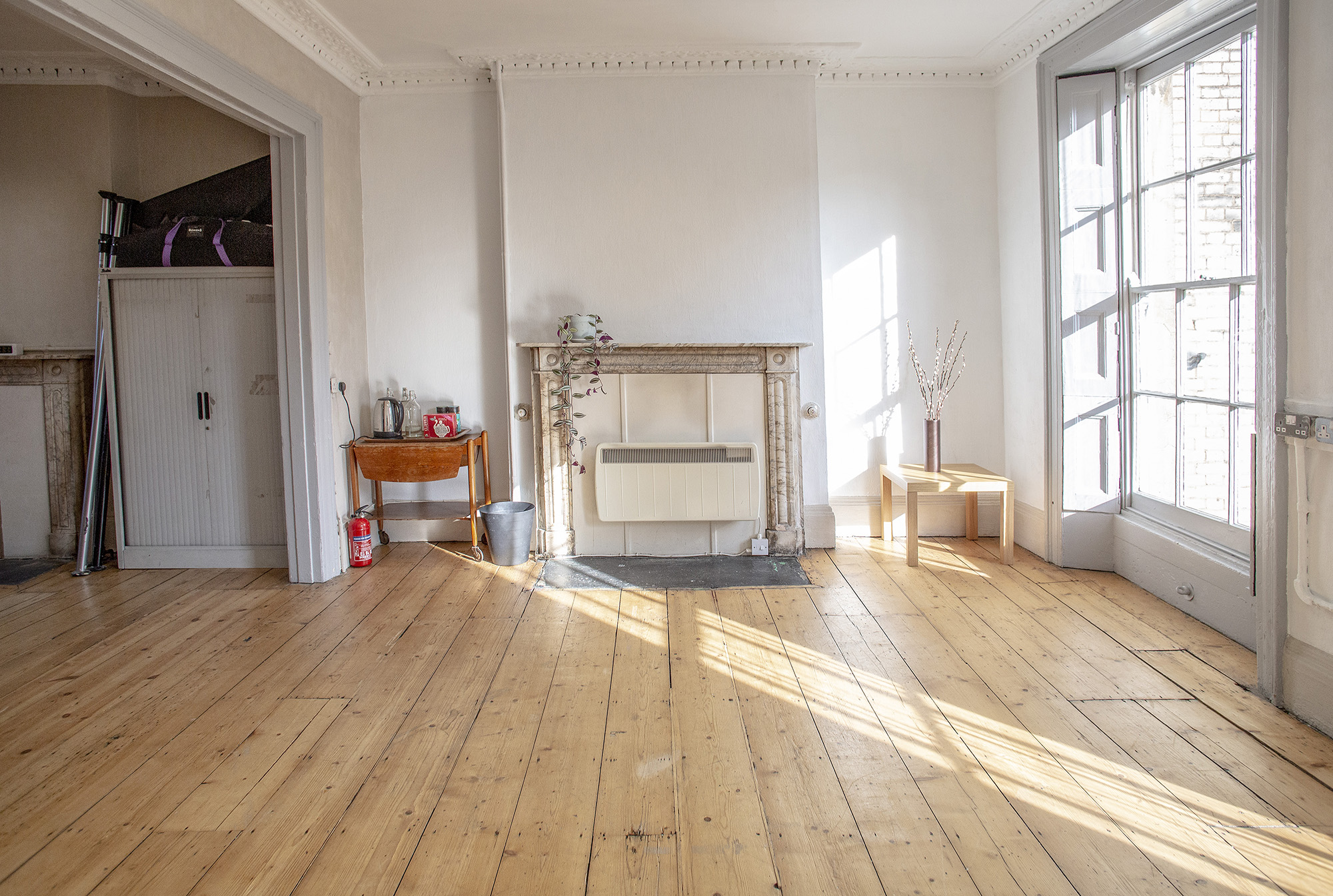 Bright, blank canvas photography studio at Anomalous Space, Islington, featuring wood floors, large window, and natural light - book via Conveenie.