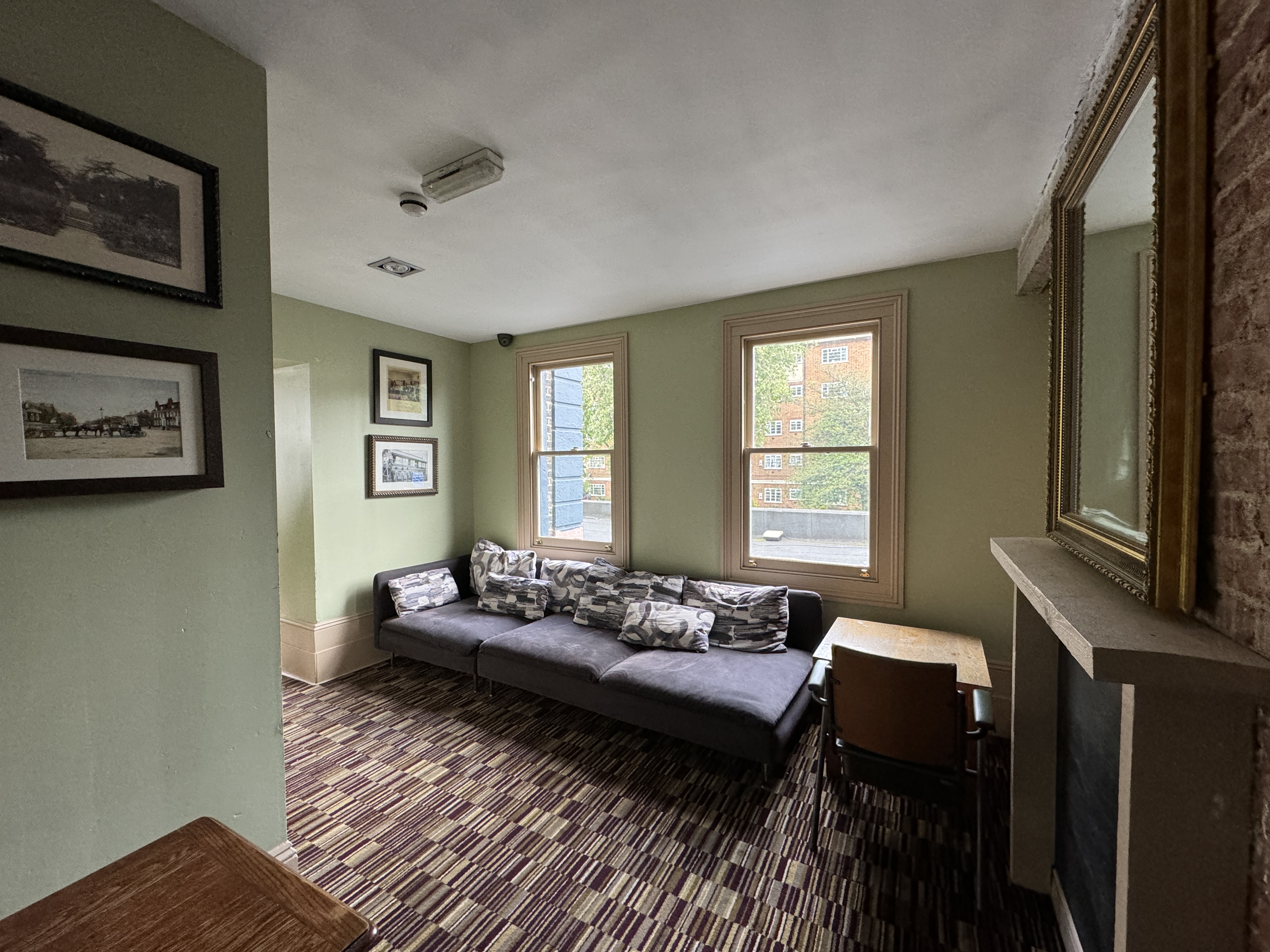 A cozy lounge corner inside the venue: sofa against wall, windows, framed artwork, soft lighting in the function room.